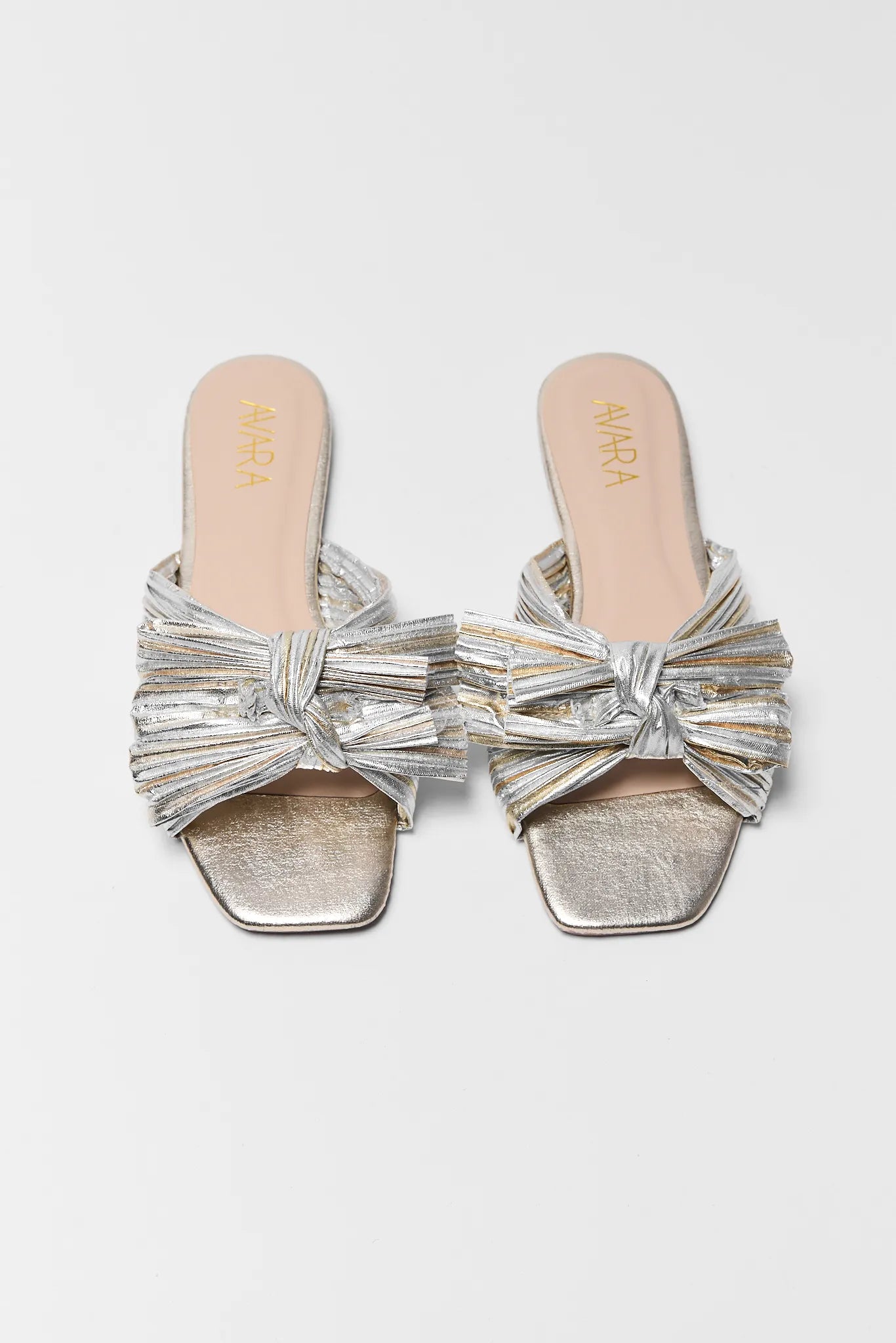 Silver sandals with bow details on a light gray background