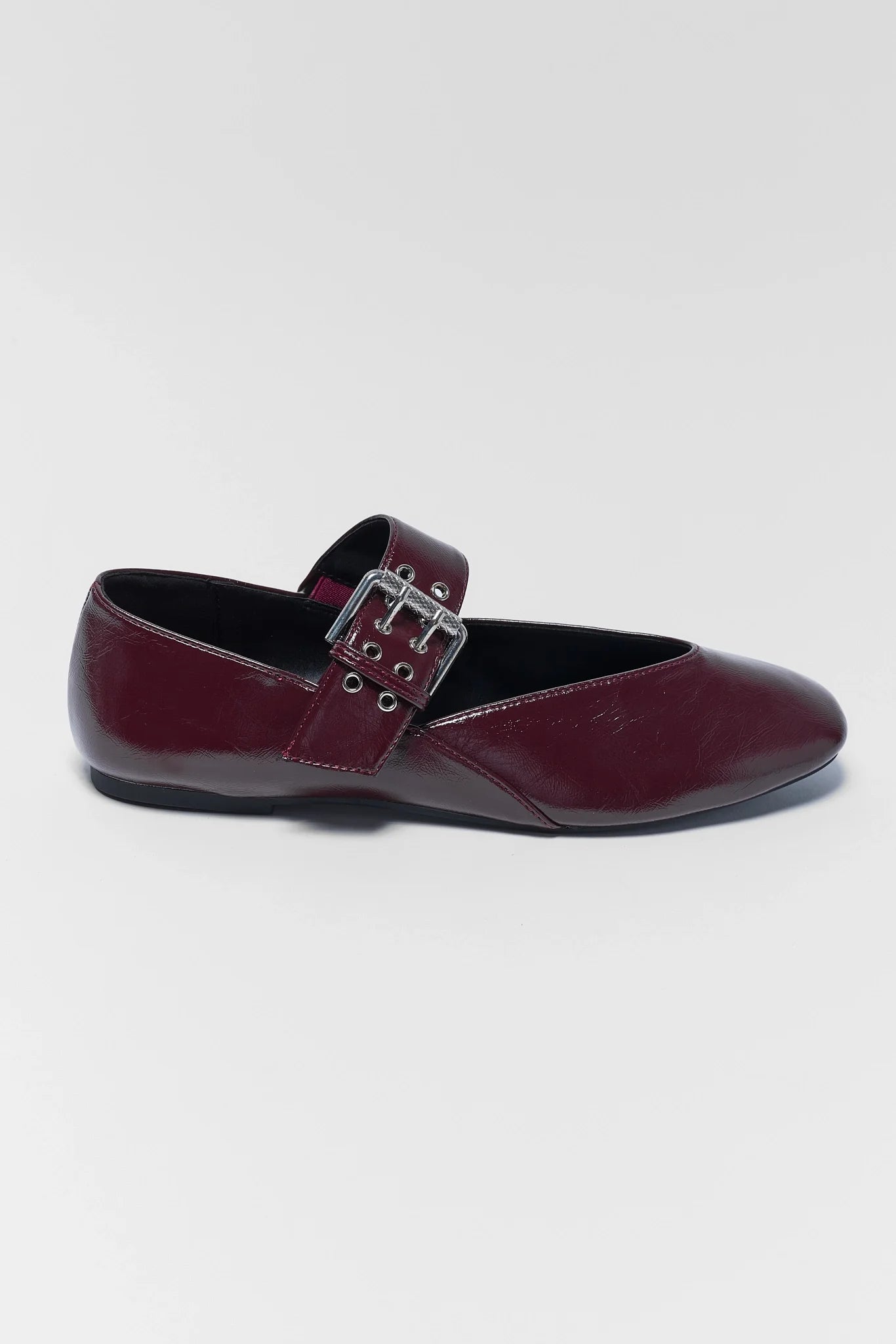 Maroon faux leather flats on a light gray background