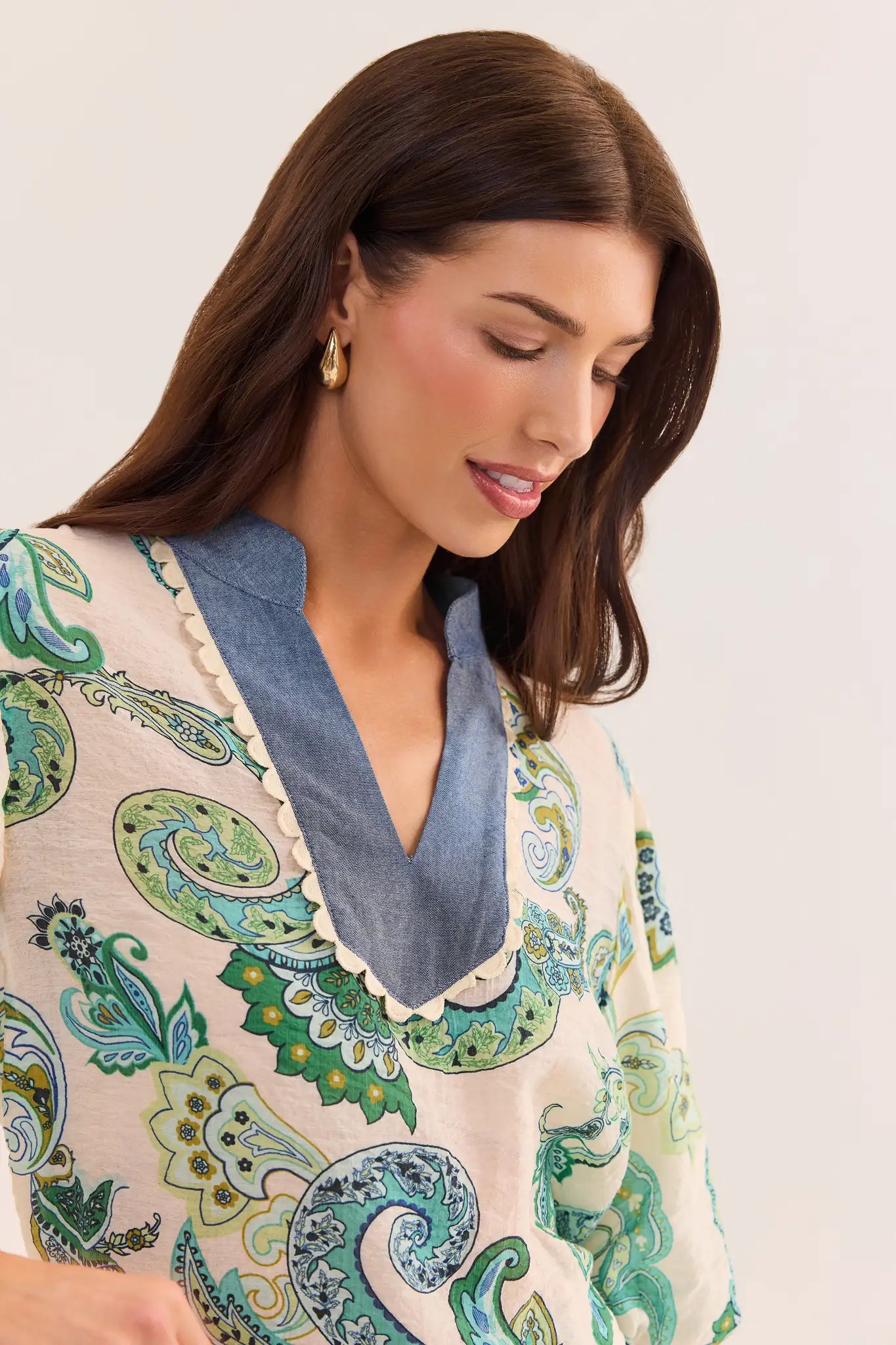 close up Woman wearing a patterned blouse with a blue collar against a white background