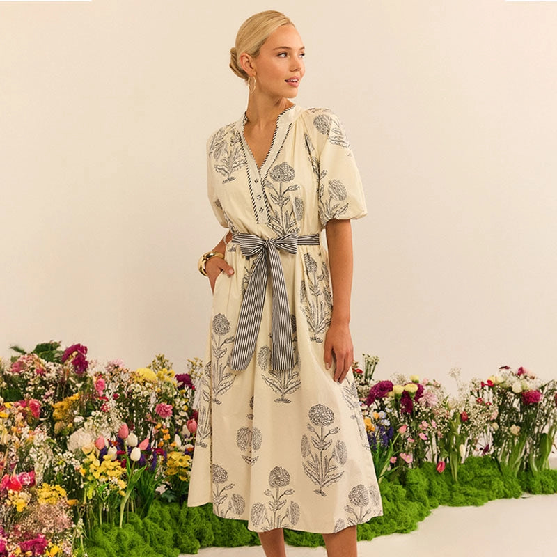Woman in a floral dress standing in front of a flower garden