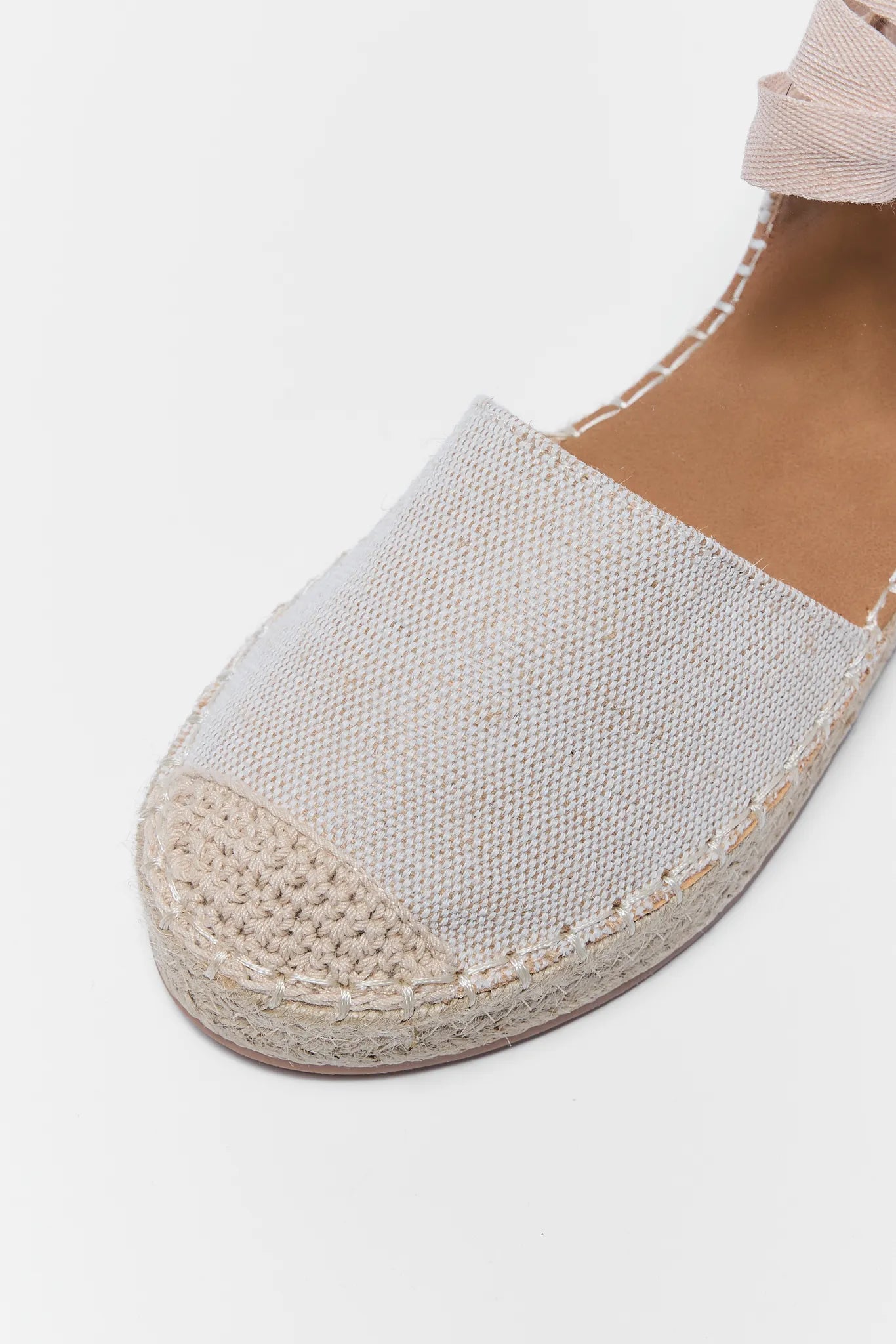 close up of beige espadrille wedge on white background
