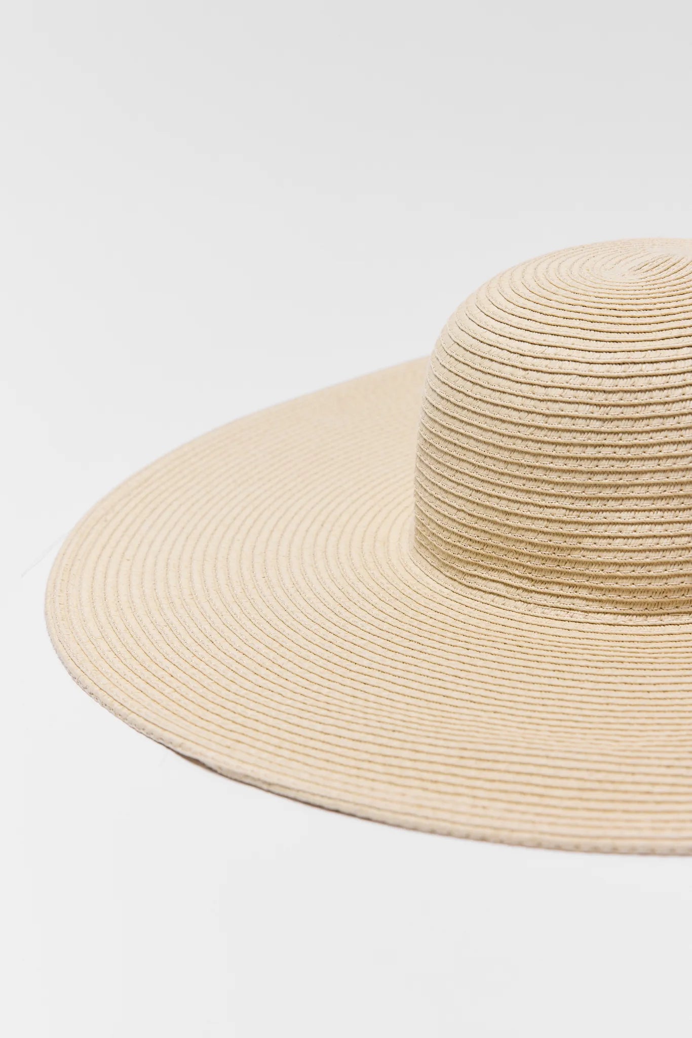 Close-up of the Betty Raffia Wide Brim Sun Hat, showcasing its wide, floppy brim and round crown with a detailed woven straw pattern.