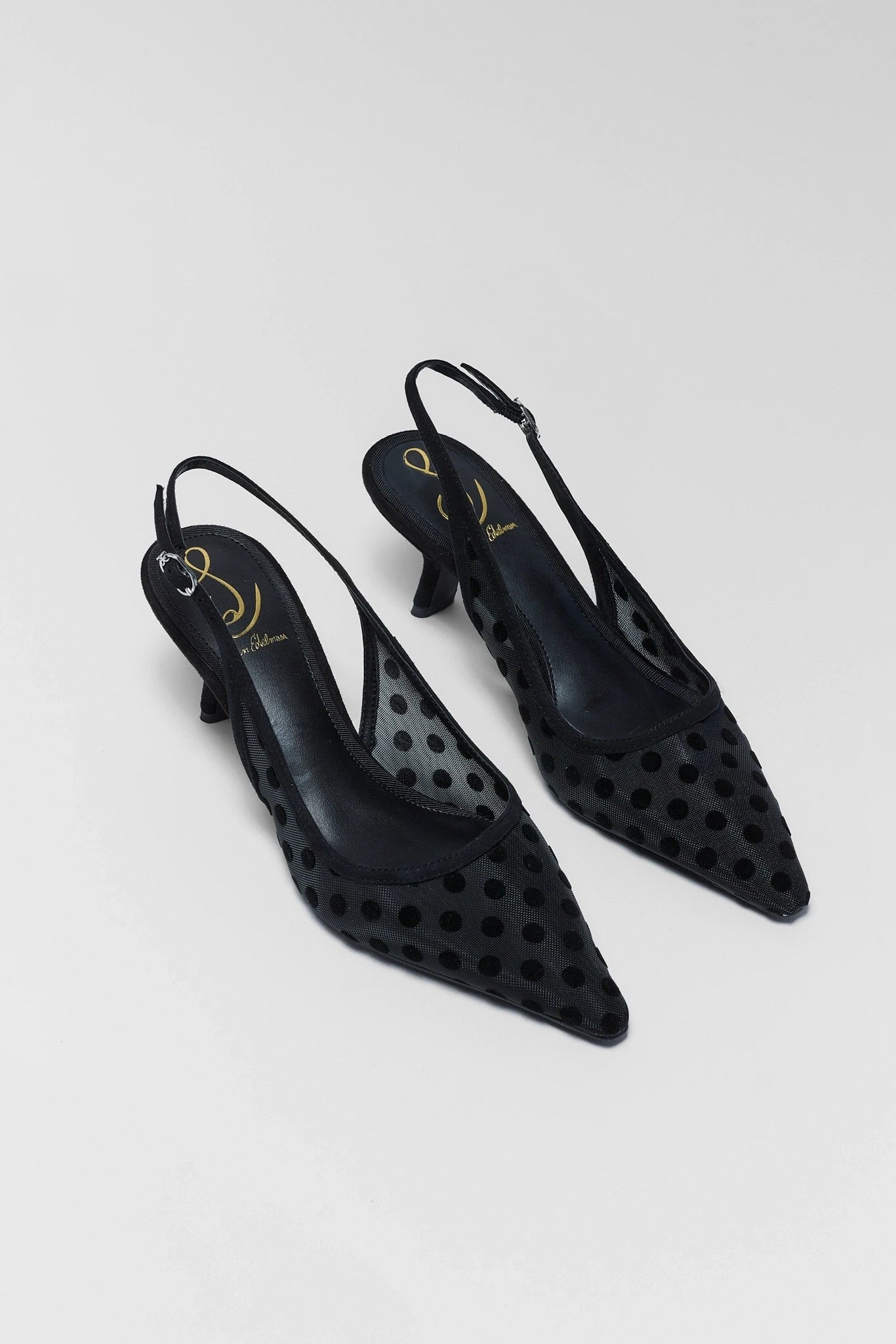 Black perforated high-heeled shoes on a light gray background