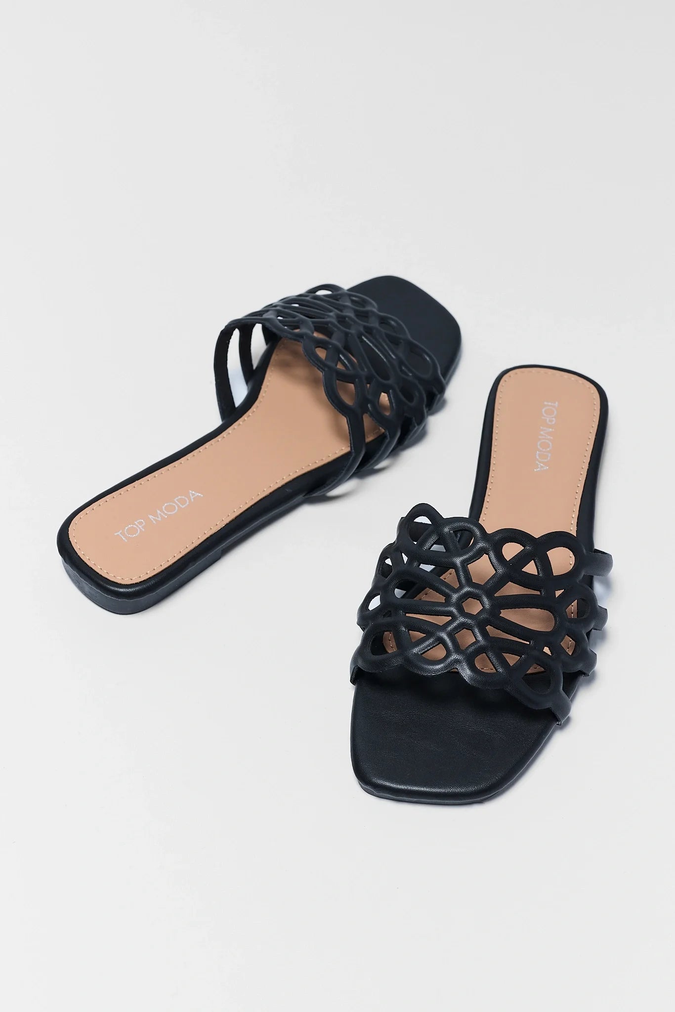 Black strappy sandals on a light gray background