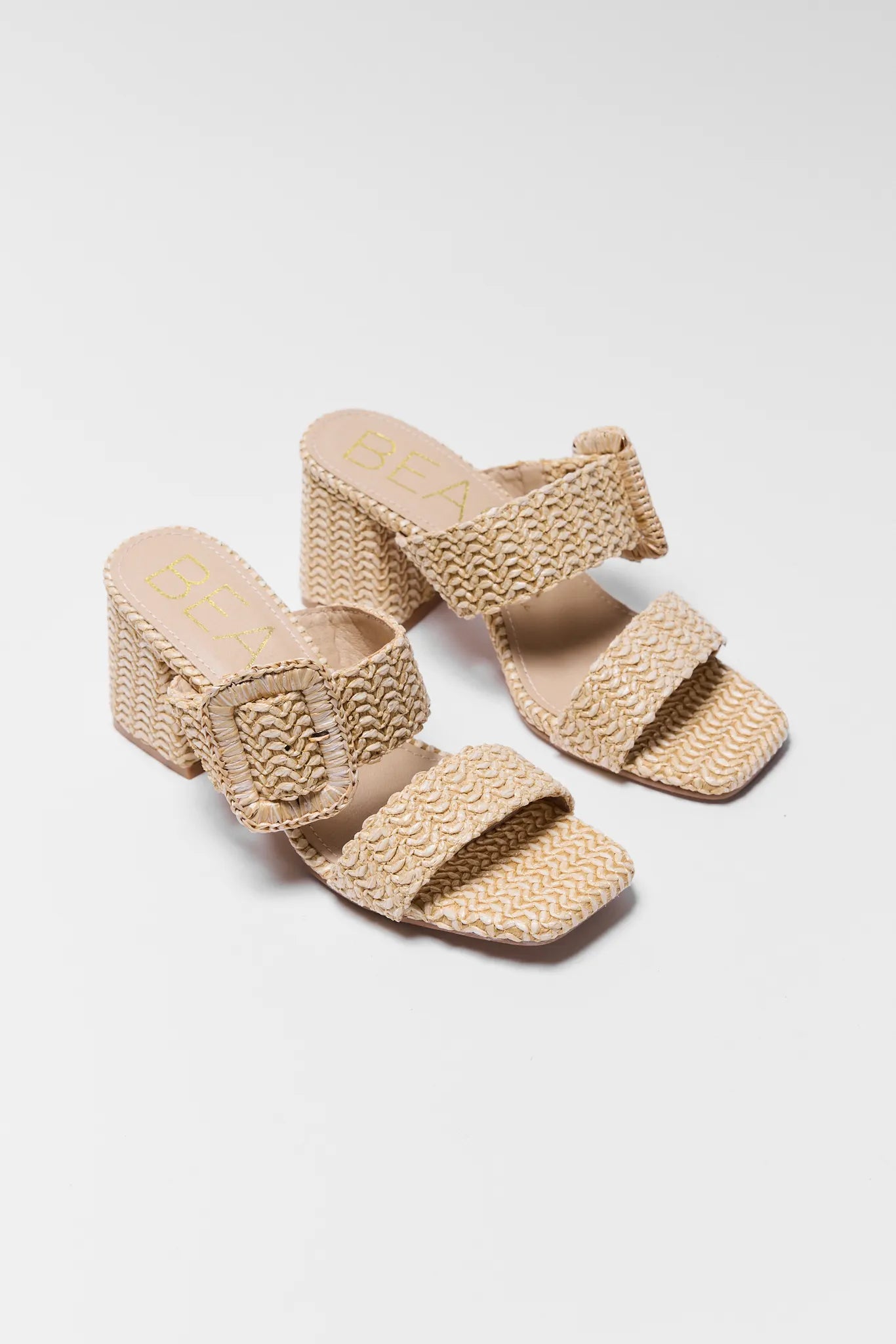 Pair of beige woven sandals on a white background