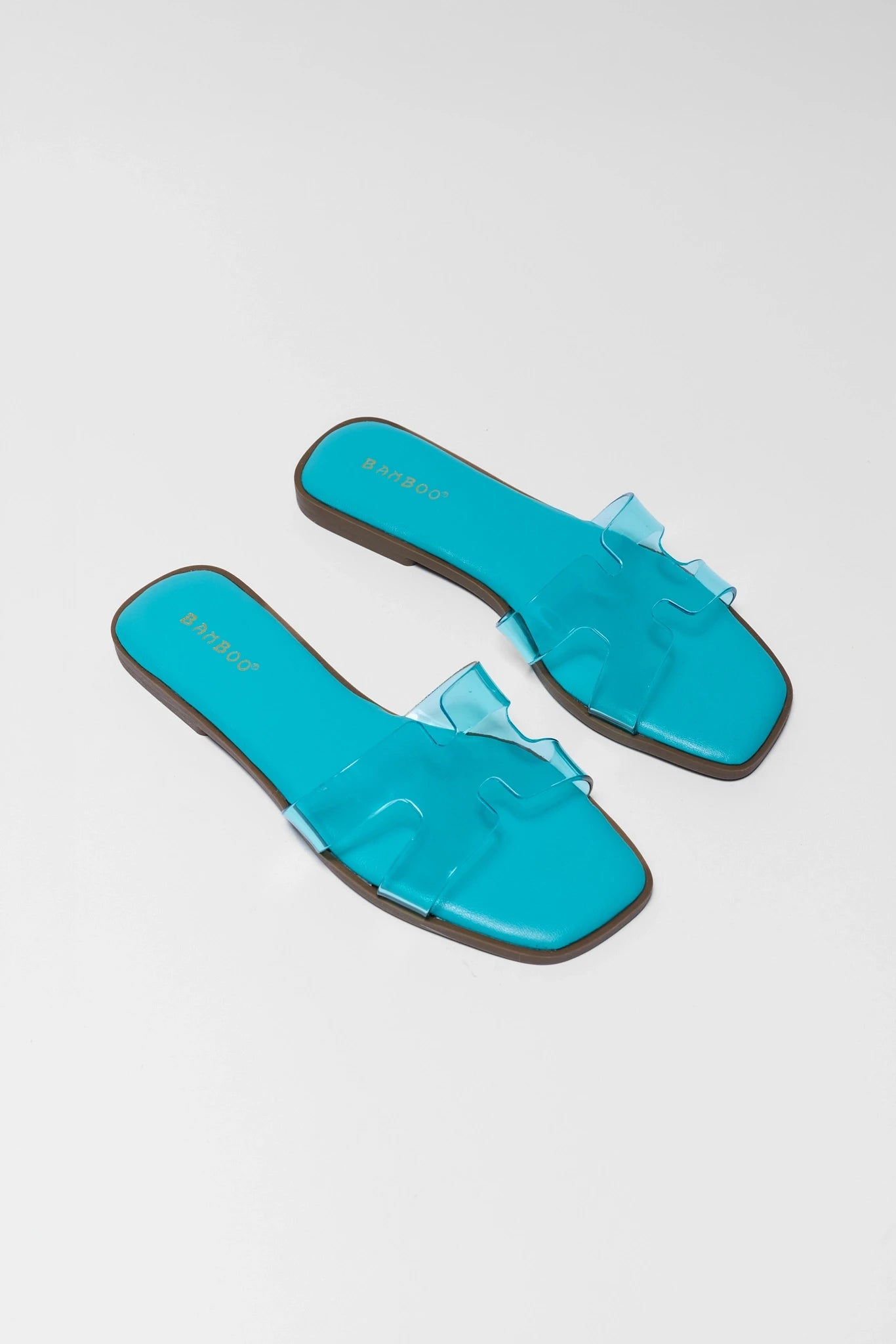 Pair of turquoise sandals with black soles on a light background