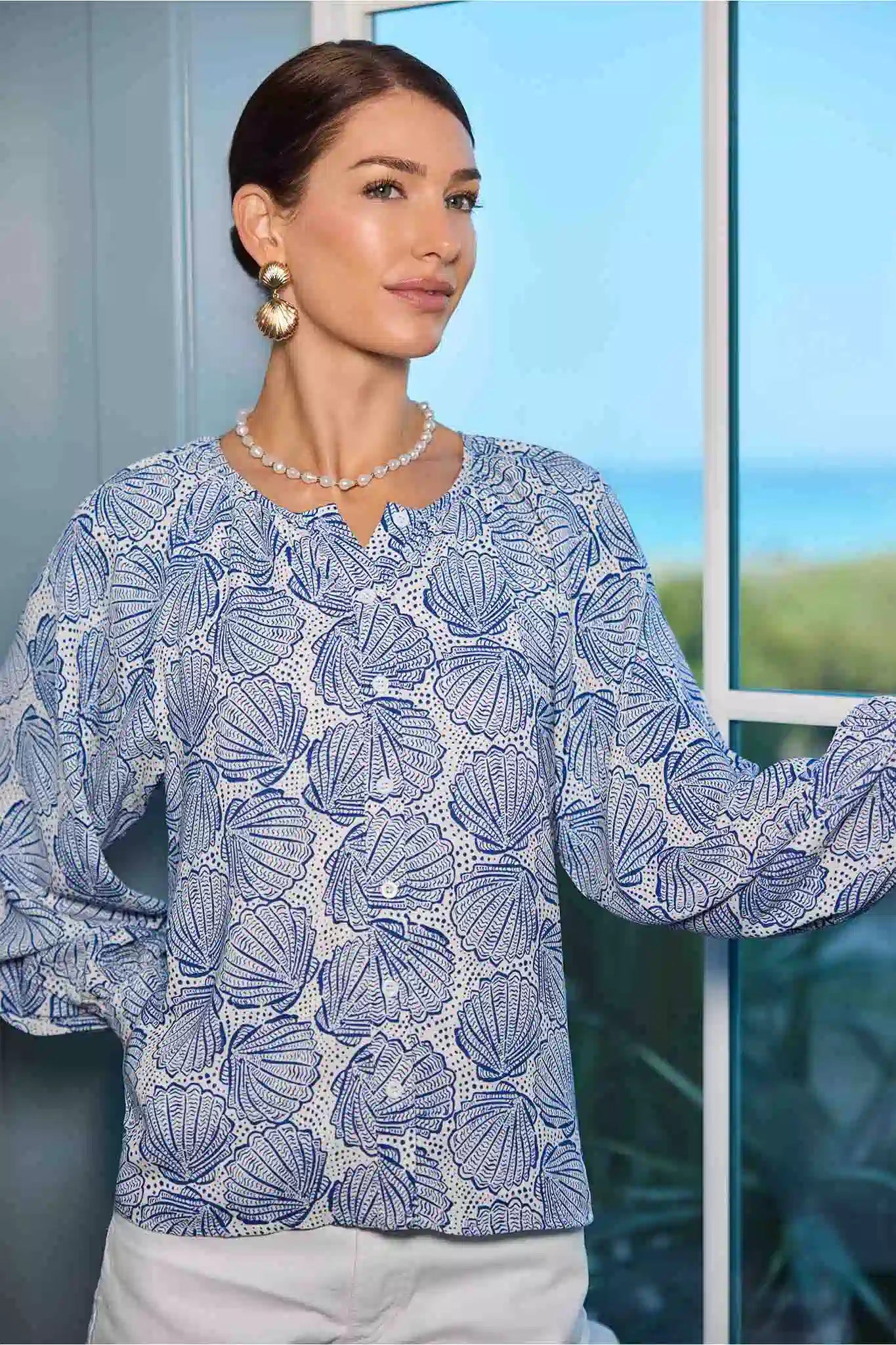 Woman wearing a blue patterned blouse with a blurred outdoor background