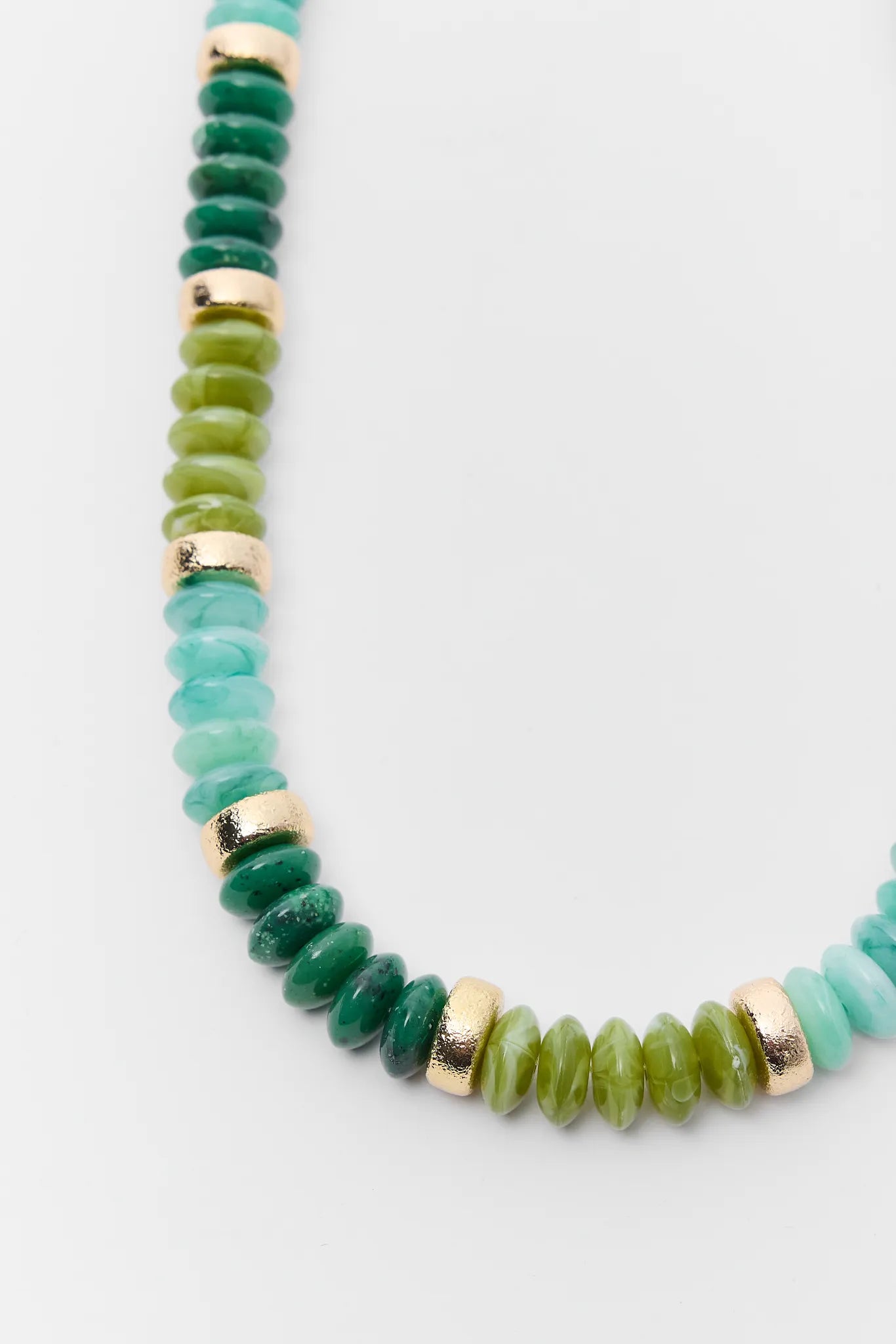Green beaded necklace with gold accents on a light gray background