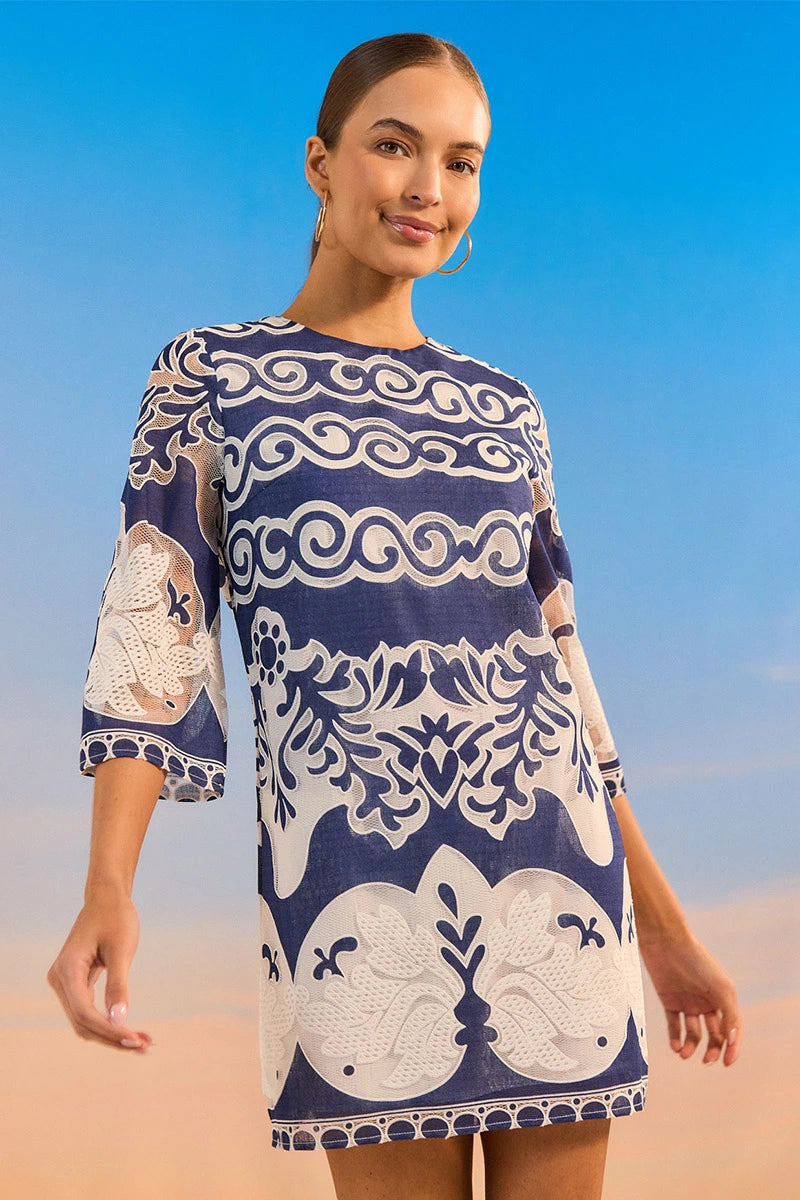 Woman wearing a blue and white patterned dress against a clear blue sky.