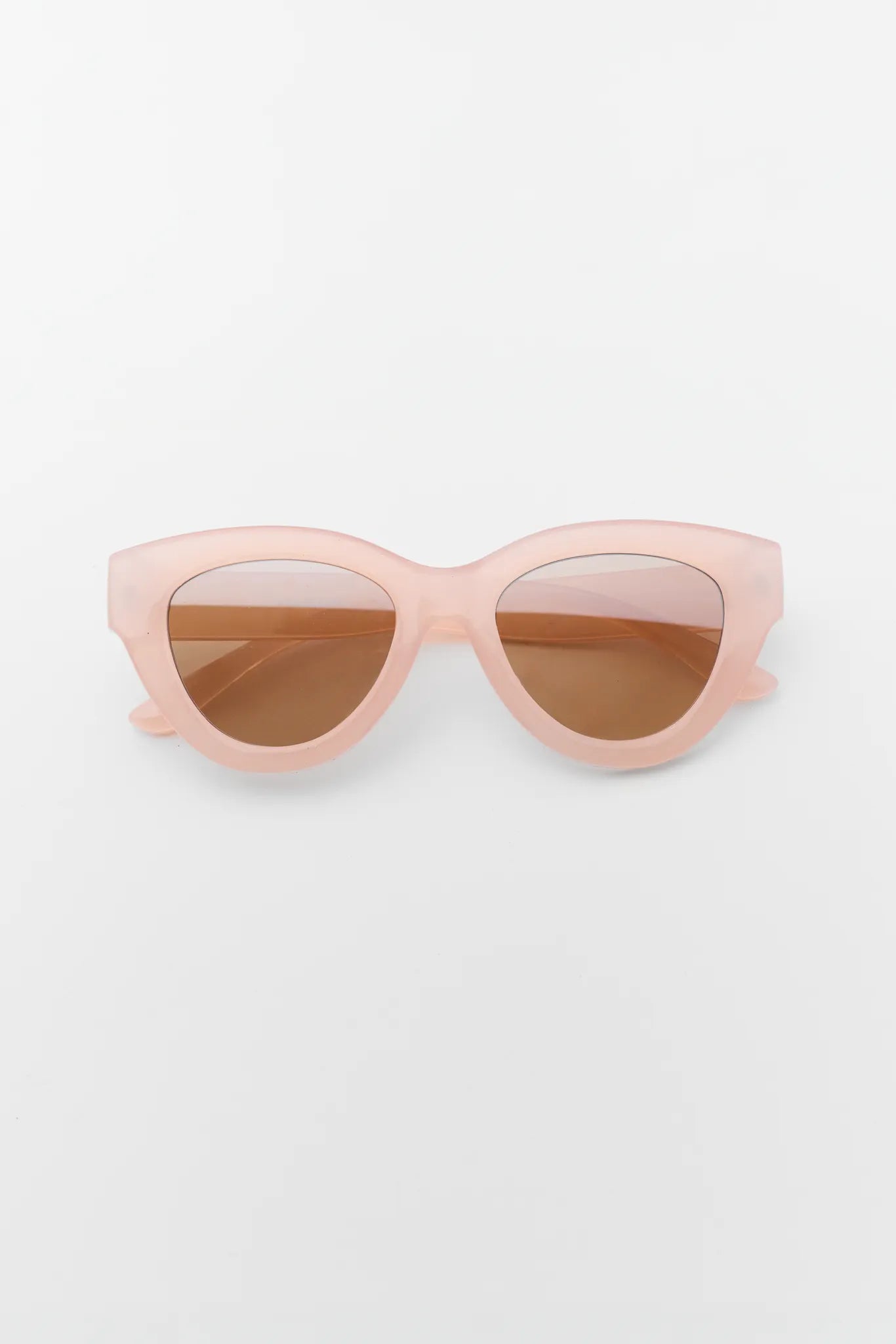Pink sunglasses with brown lenses on a white background
