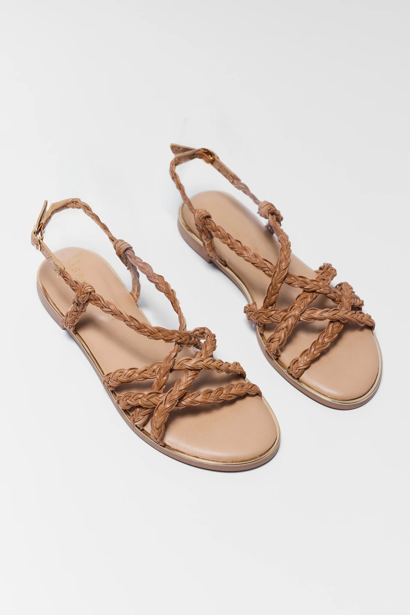 Pair of beige sandals with braided straps on a light gray background two