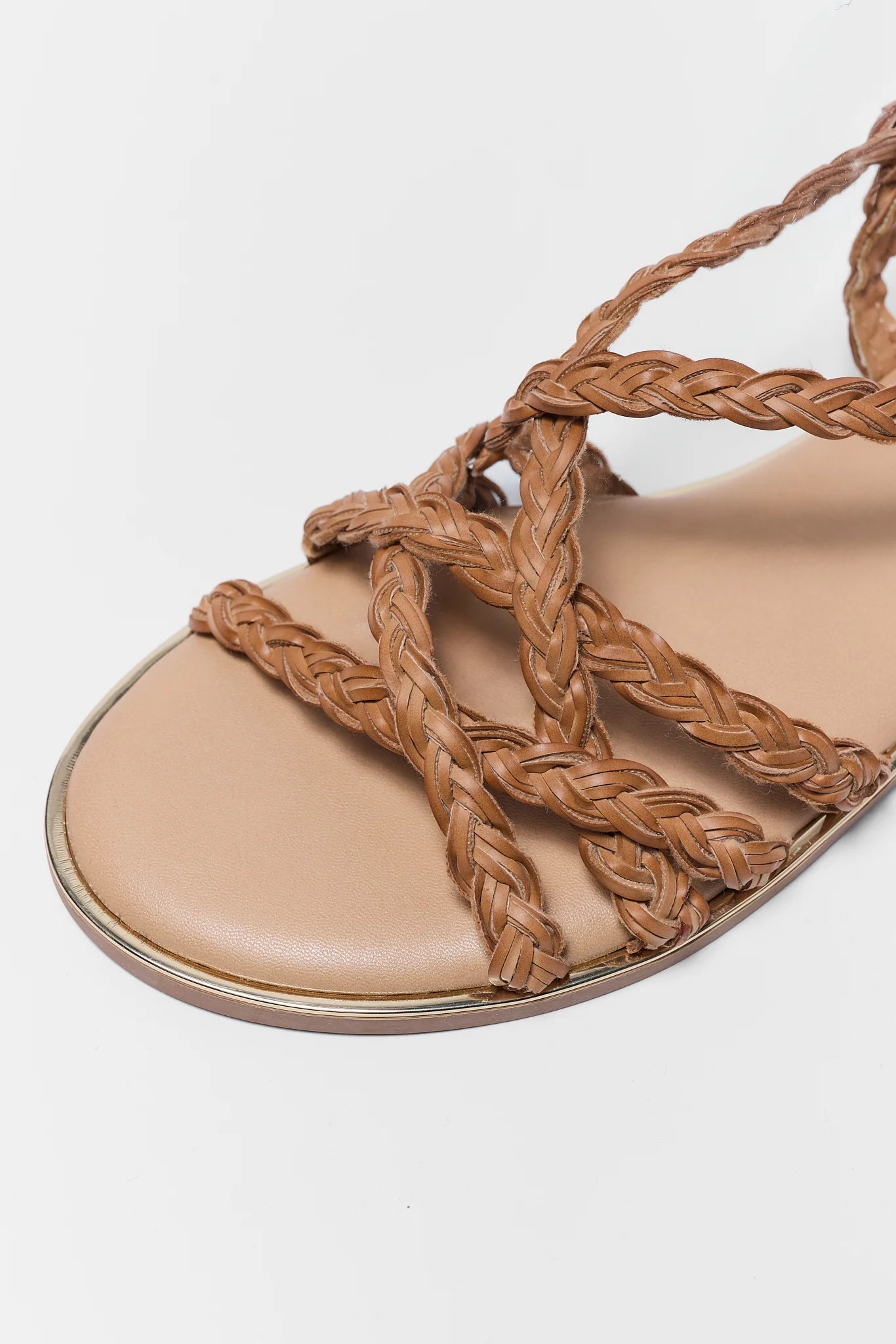 Beige sandal with braided straps on a white background close up