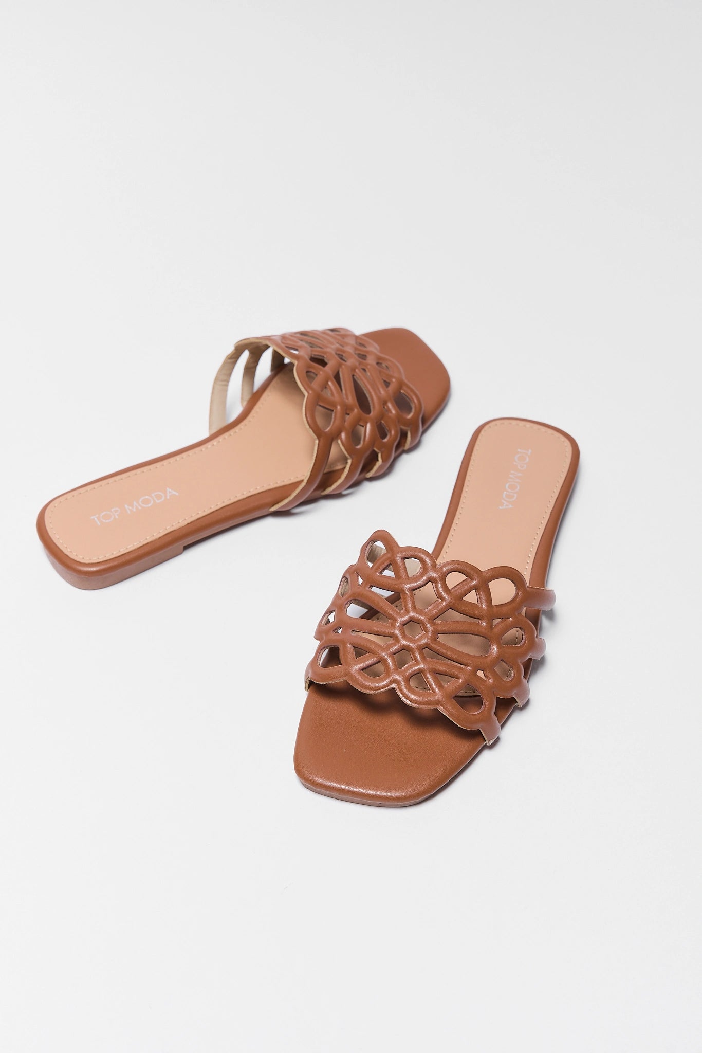 Pair of brown sandals with intricate cut-out design on a white background