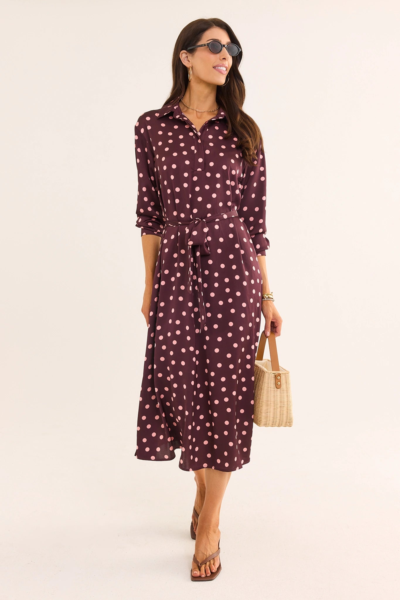 woman wearing brown polka dot dress walking on cream background