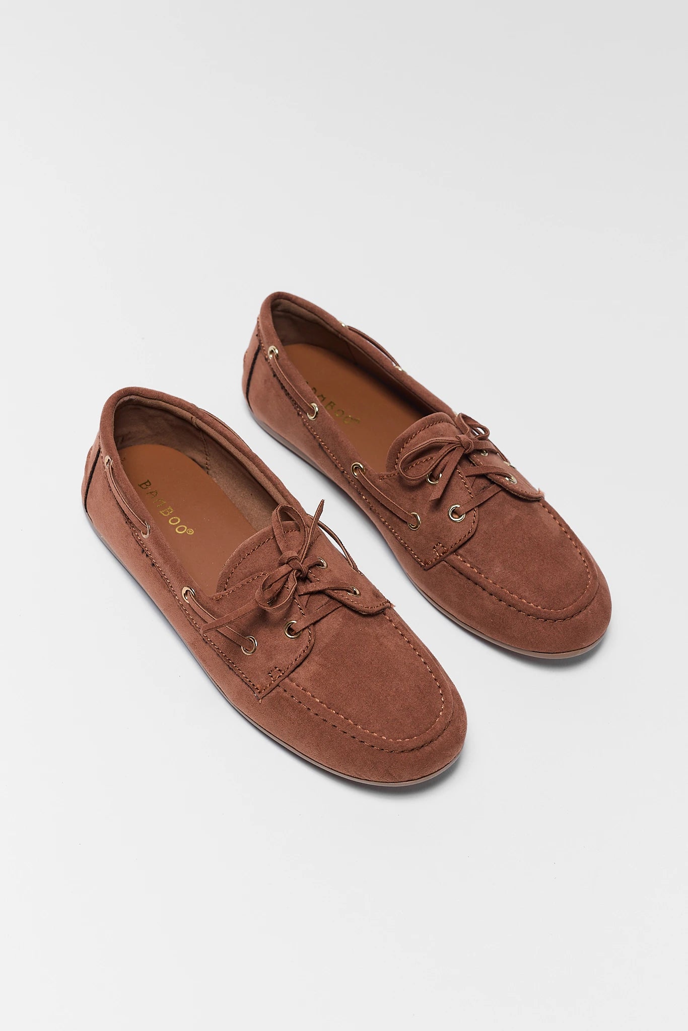 Pair of brown suede loafers on a light gray background stand