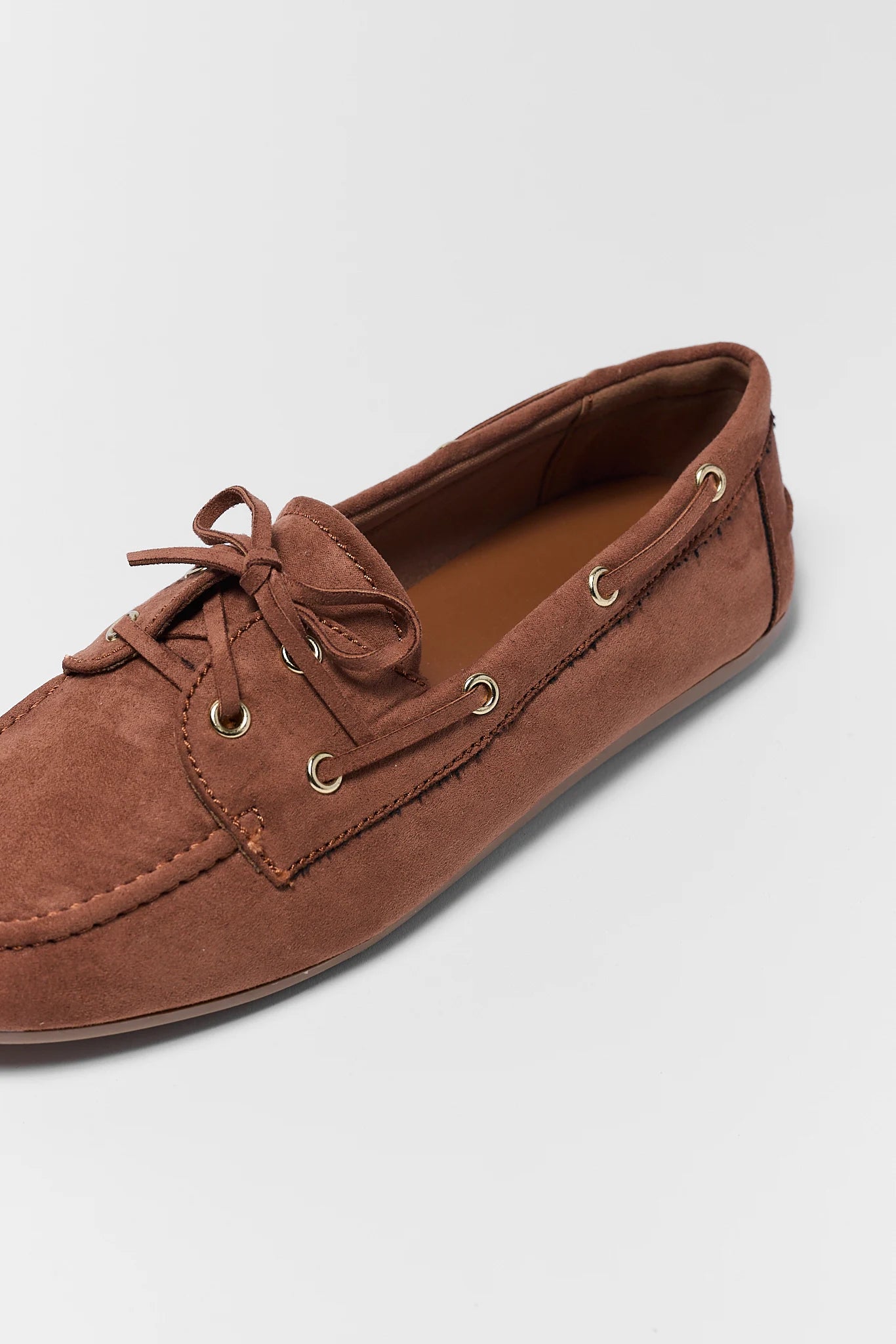Brown suede loafer shoe on a light gray background close up 