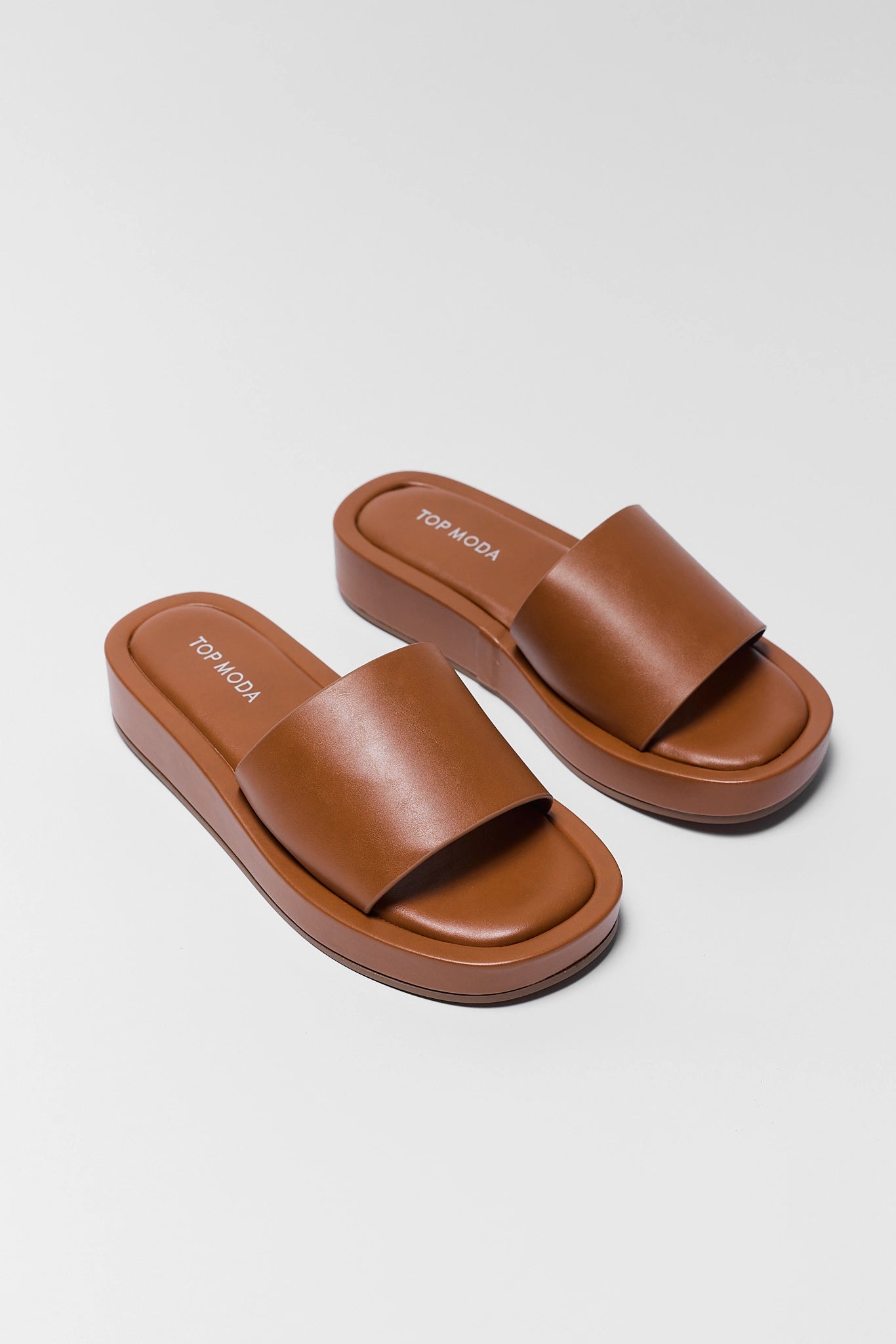 two Pair of brown sandals on a light gray background