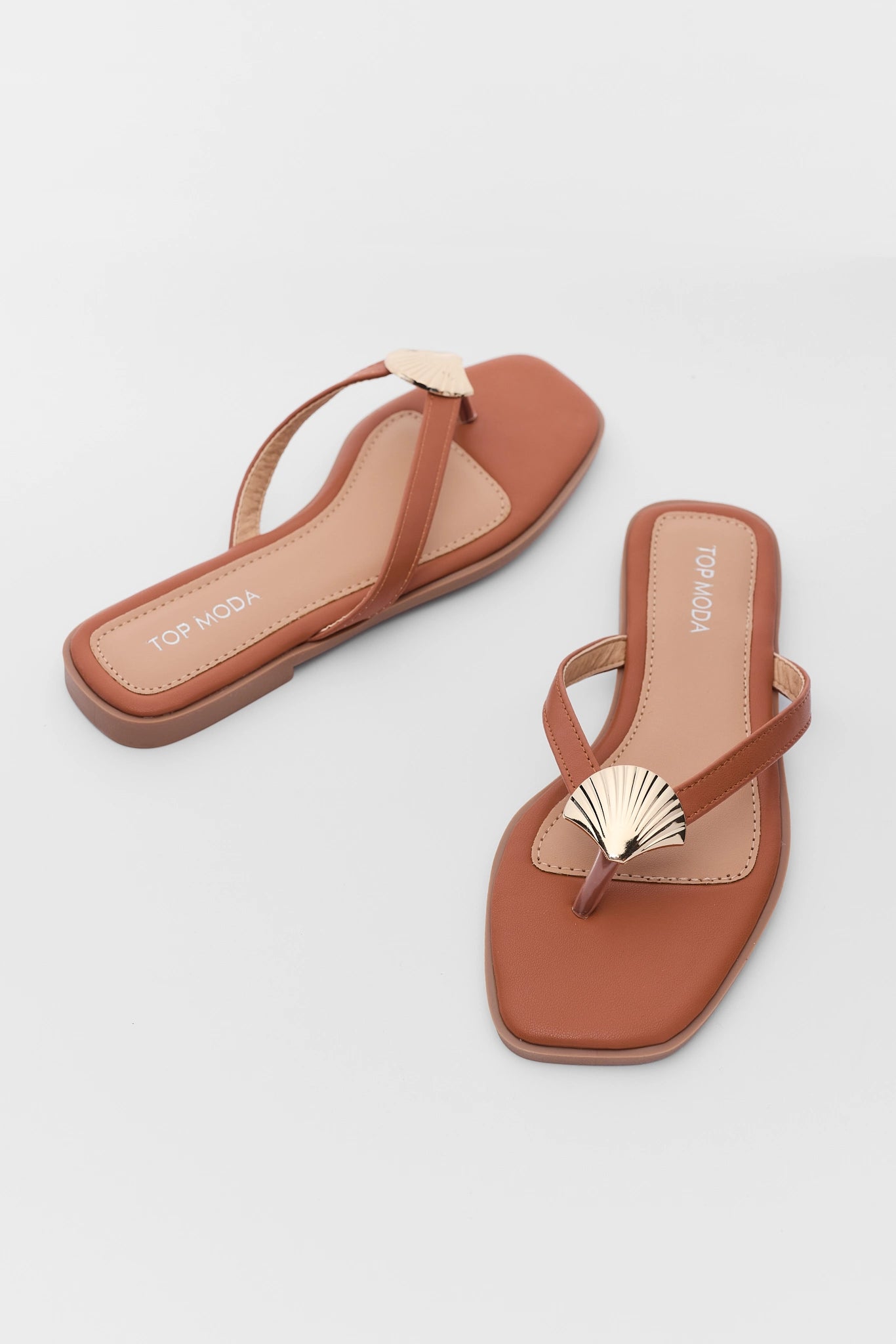 Pair of brown sandals with gold accents on a light gray background