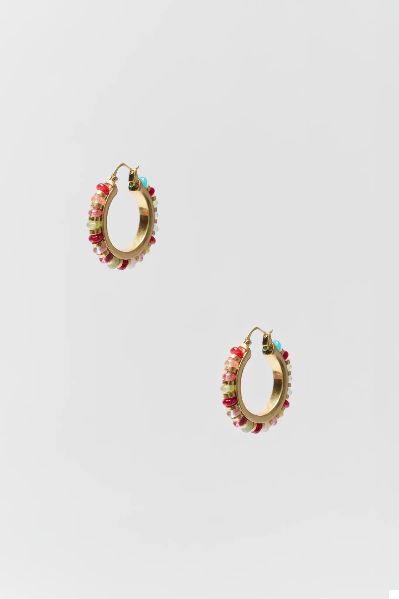 Gold hoop earrings with colorful beads on a light gray background