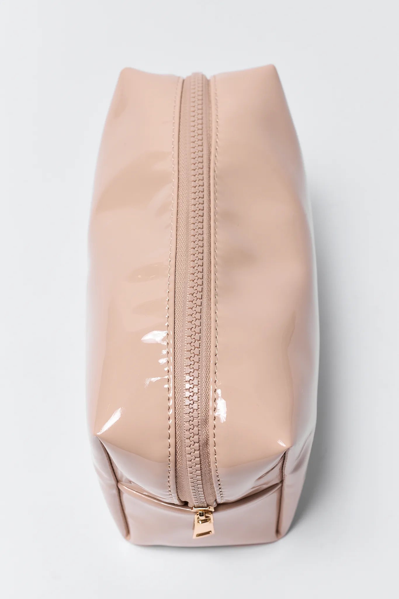 Beige cosmetic bag with a gold zipper on a light gray background