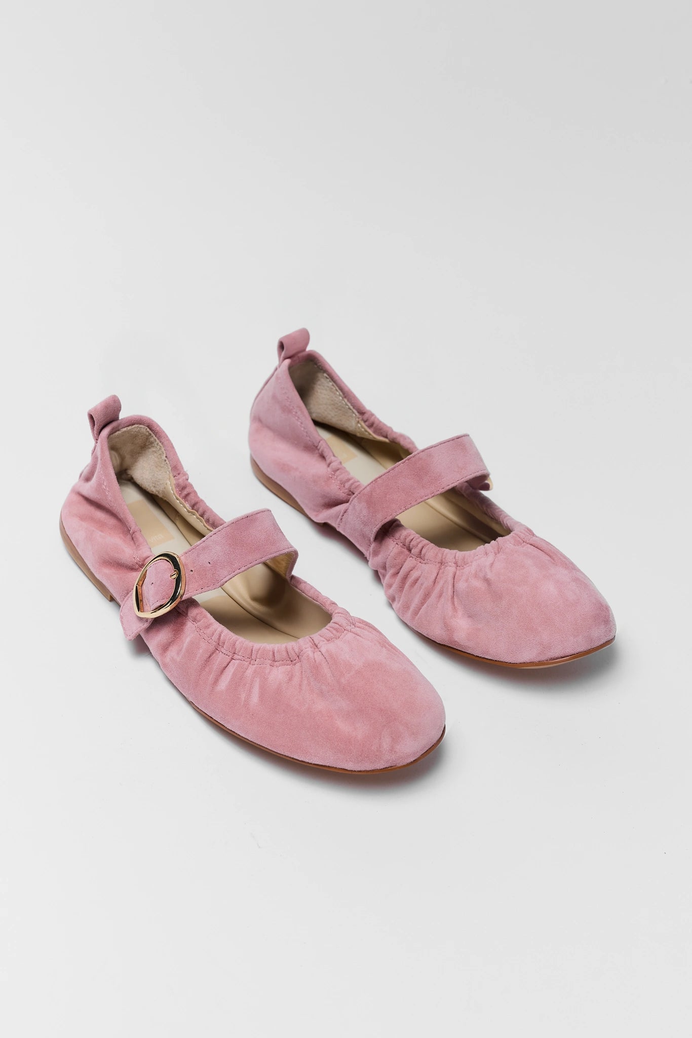 Pair of pink suede shoes with buckles on a white background