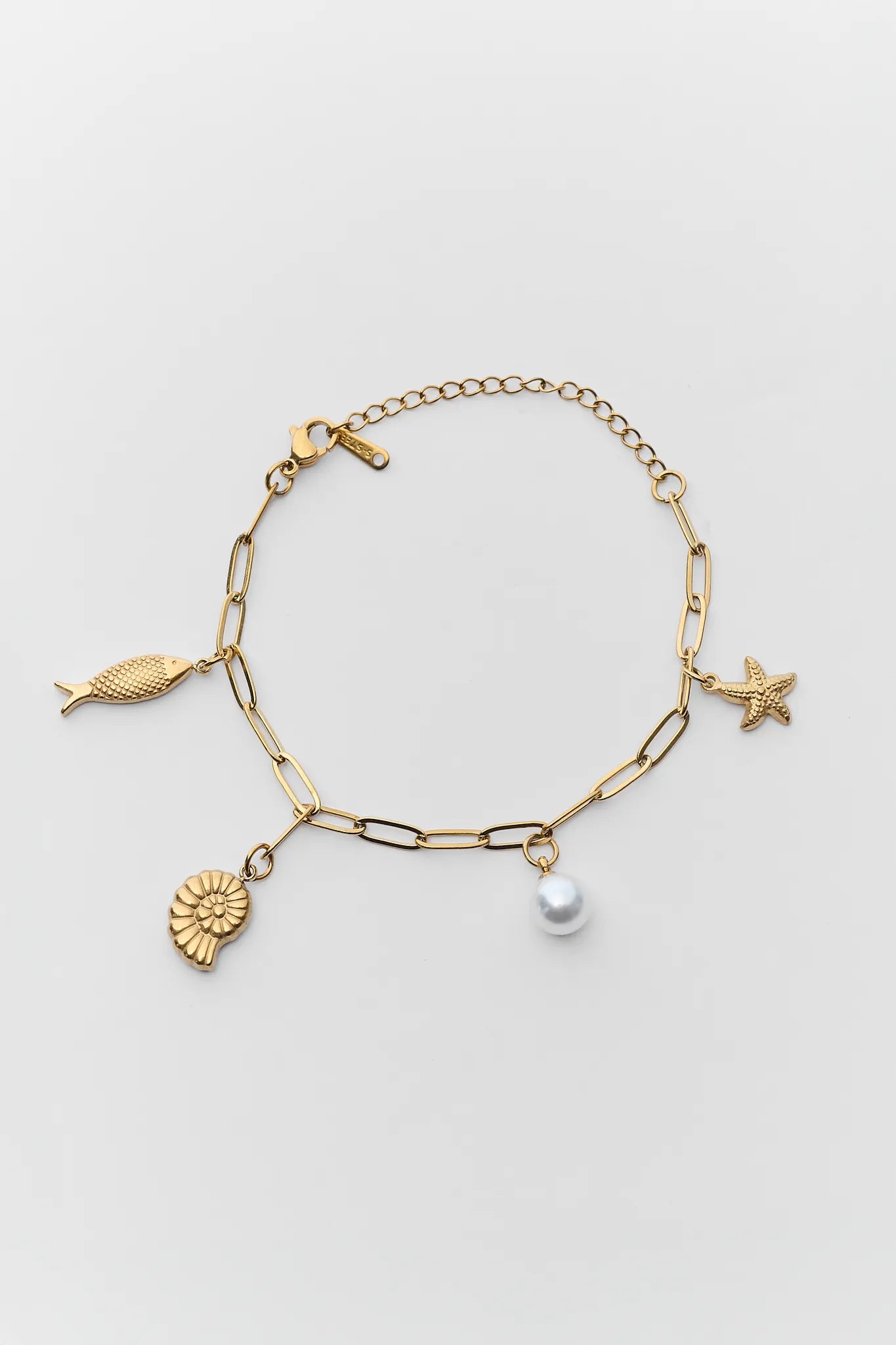 Gold bracelet with various charms on a light gray background