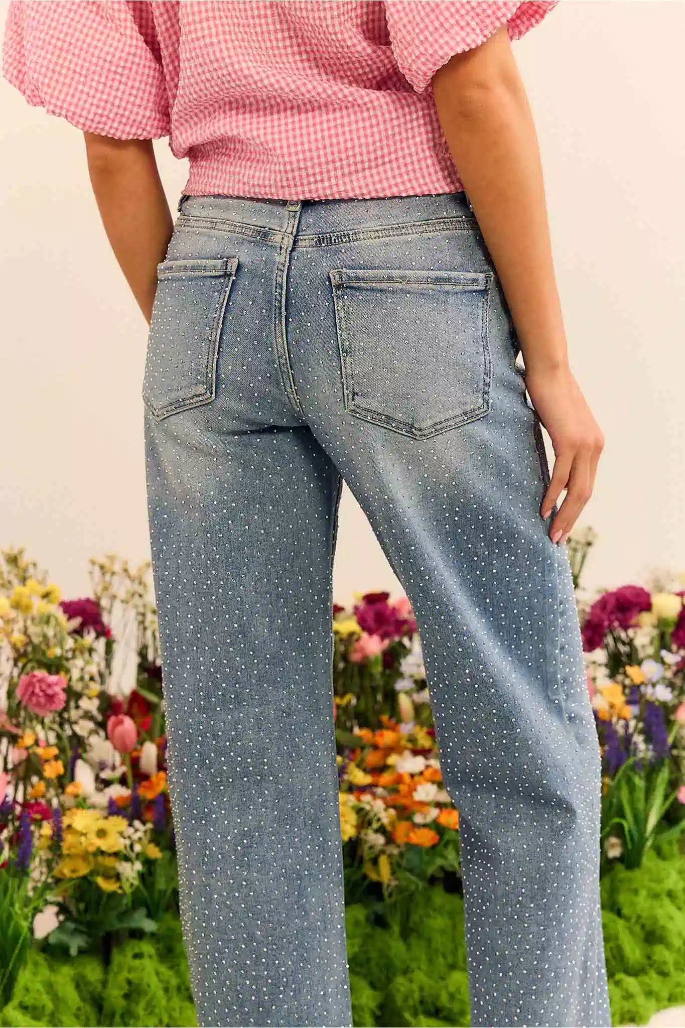 Person wearing blue jeans with a blurred floral background