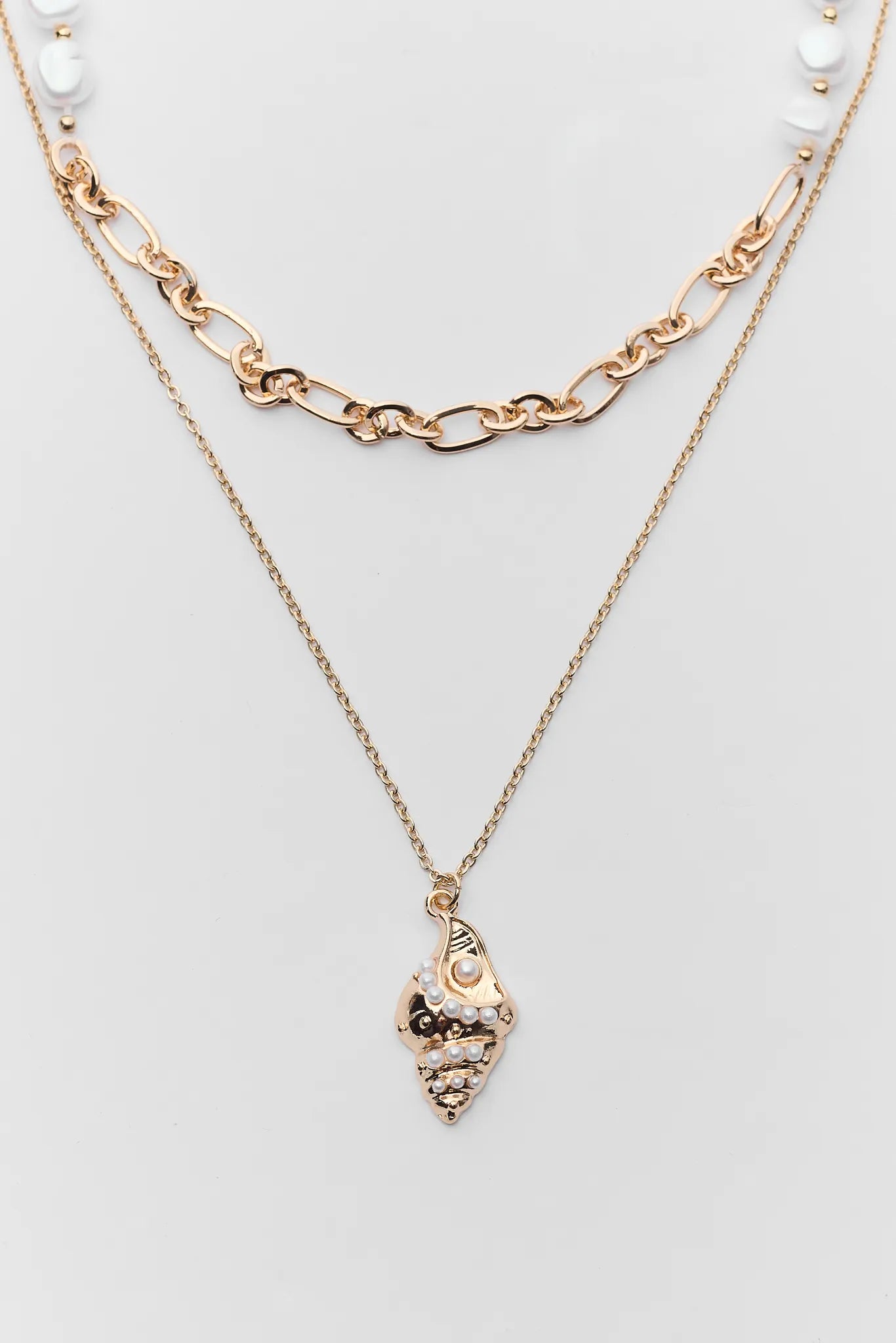 Gold necklace with a pendant on a light gray background