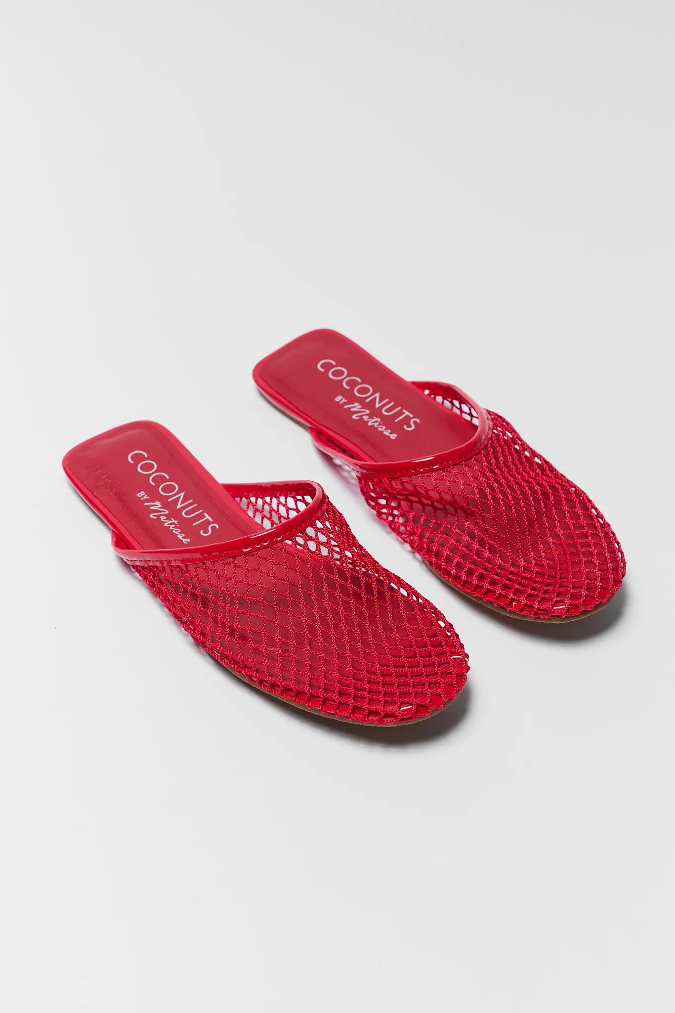 Red mesh sandals with 'Coconuts' branding on a light gray background