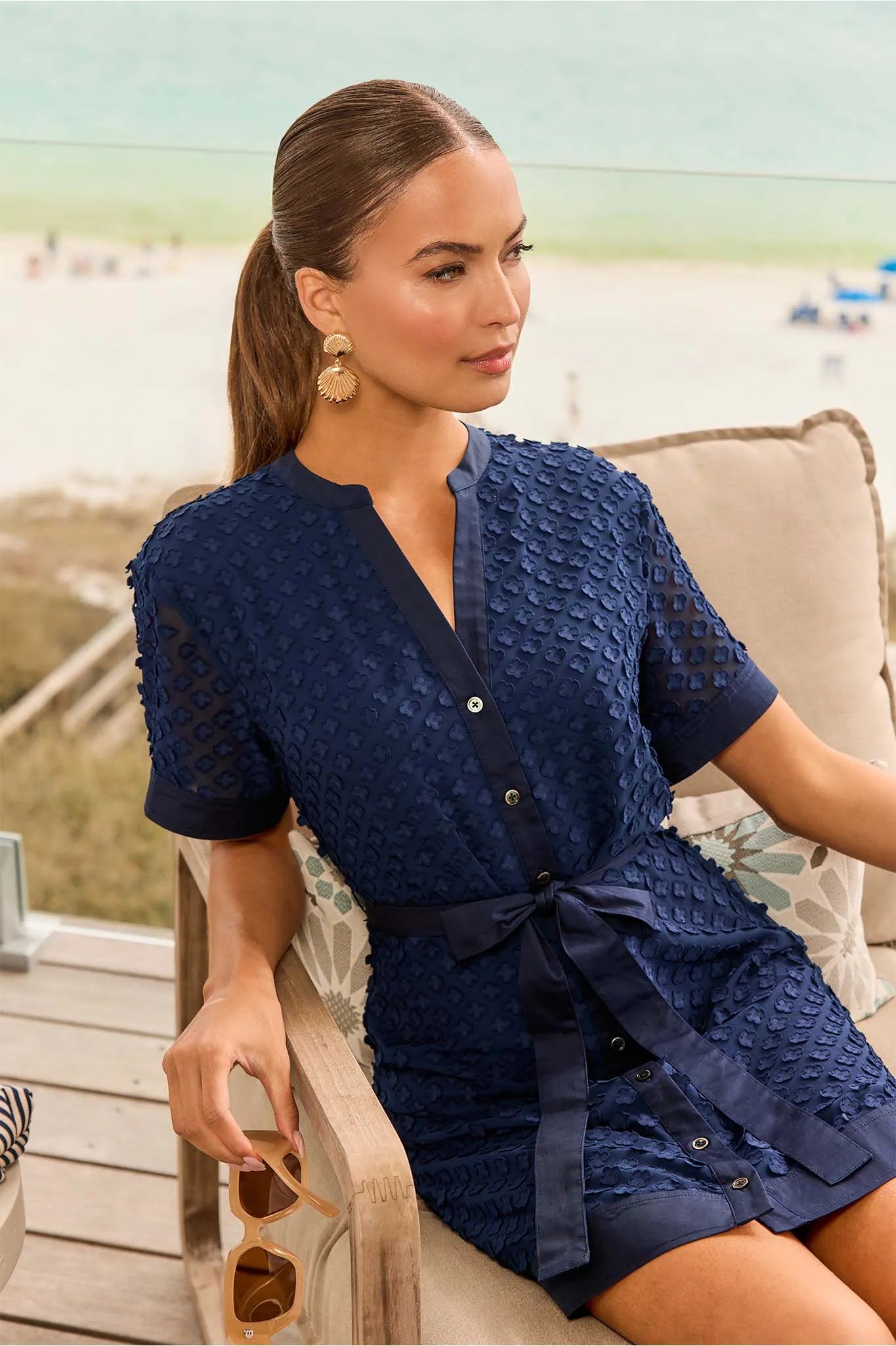 Woman in a navy dress sitting on a chair by the beach