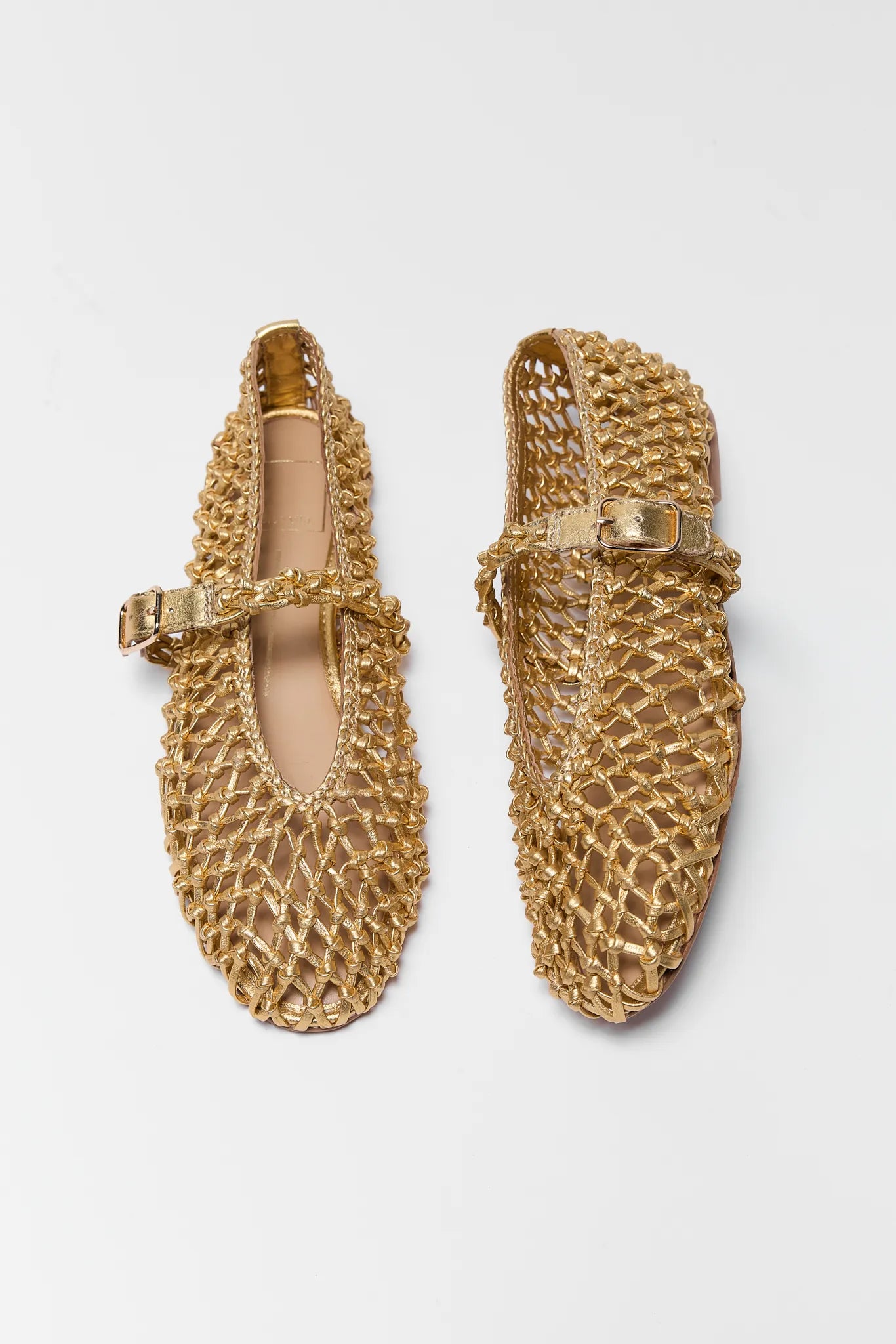 Pair of gold mesh shoes on a light gray background Clair