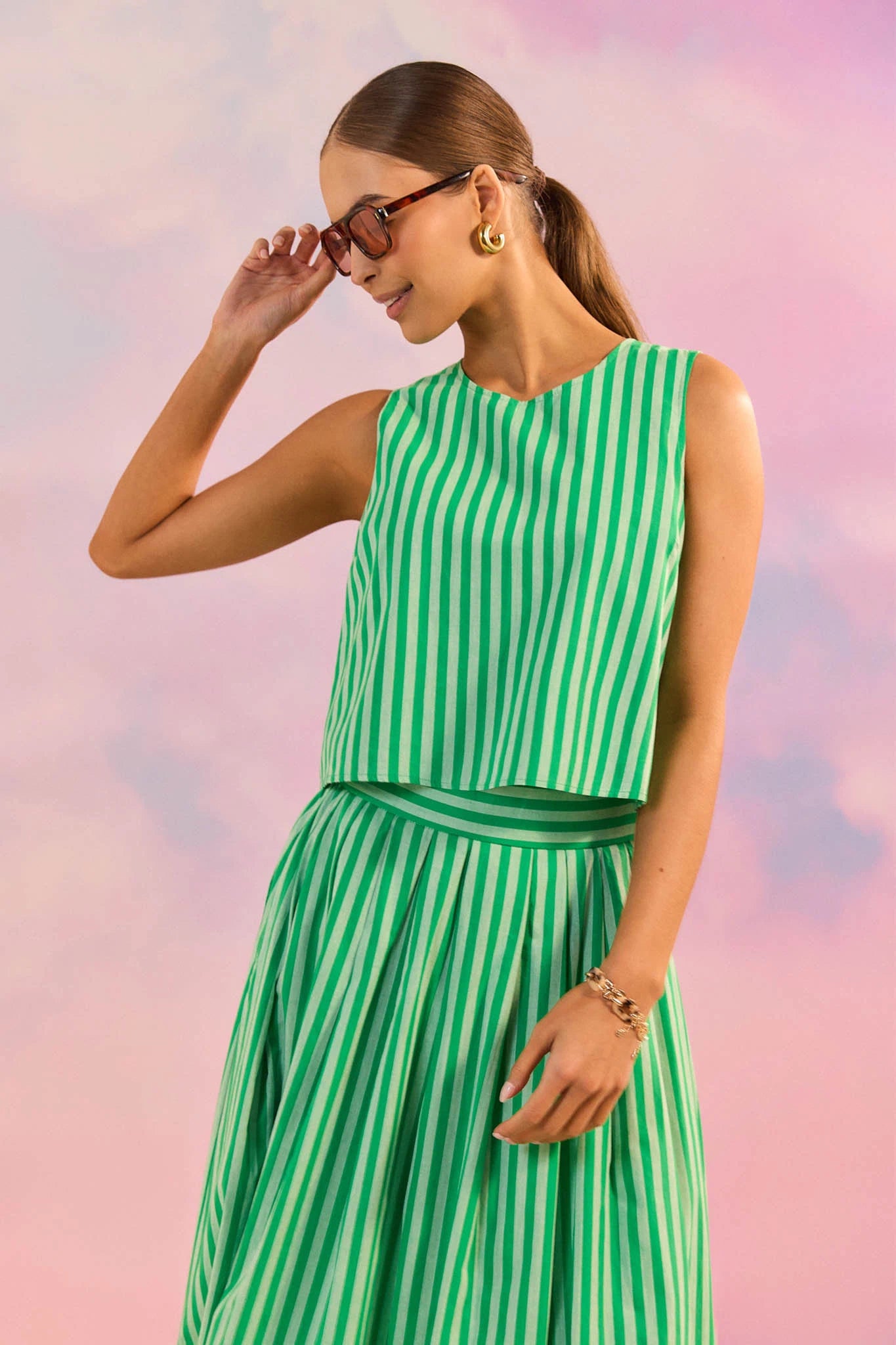 Woman wearing a green and white striped dress against a pastel sky background