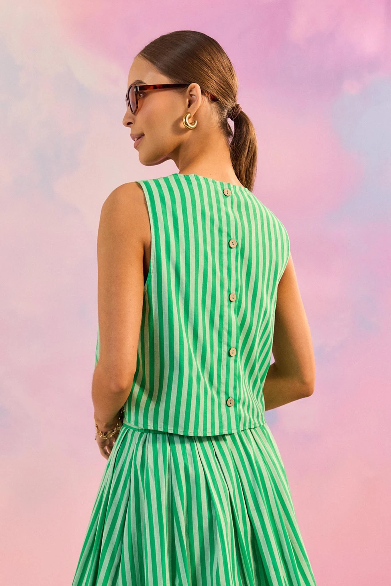 Woman wearing a green and white striped dress against a colorful, abstract background