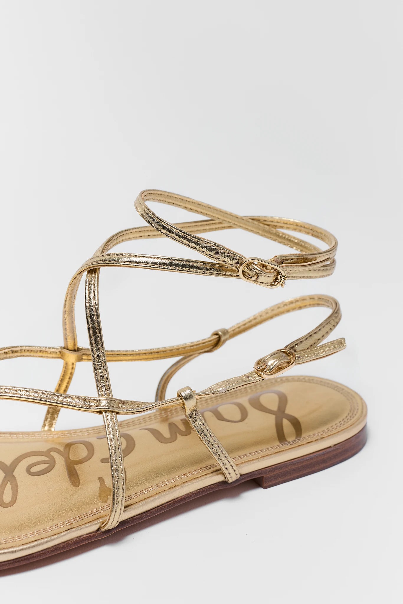 Gold strappy sandal with 'Sam Edelman' branding on a white background close up