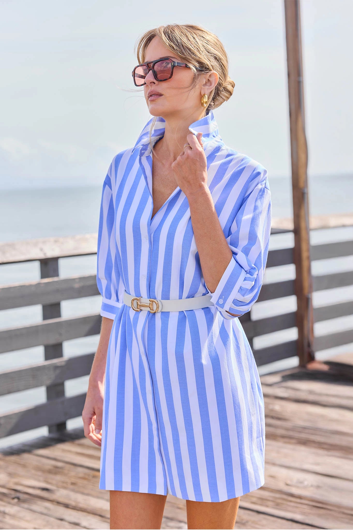 Woman wearing a blue and white striped dress on a wooden deck with ocean view