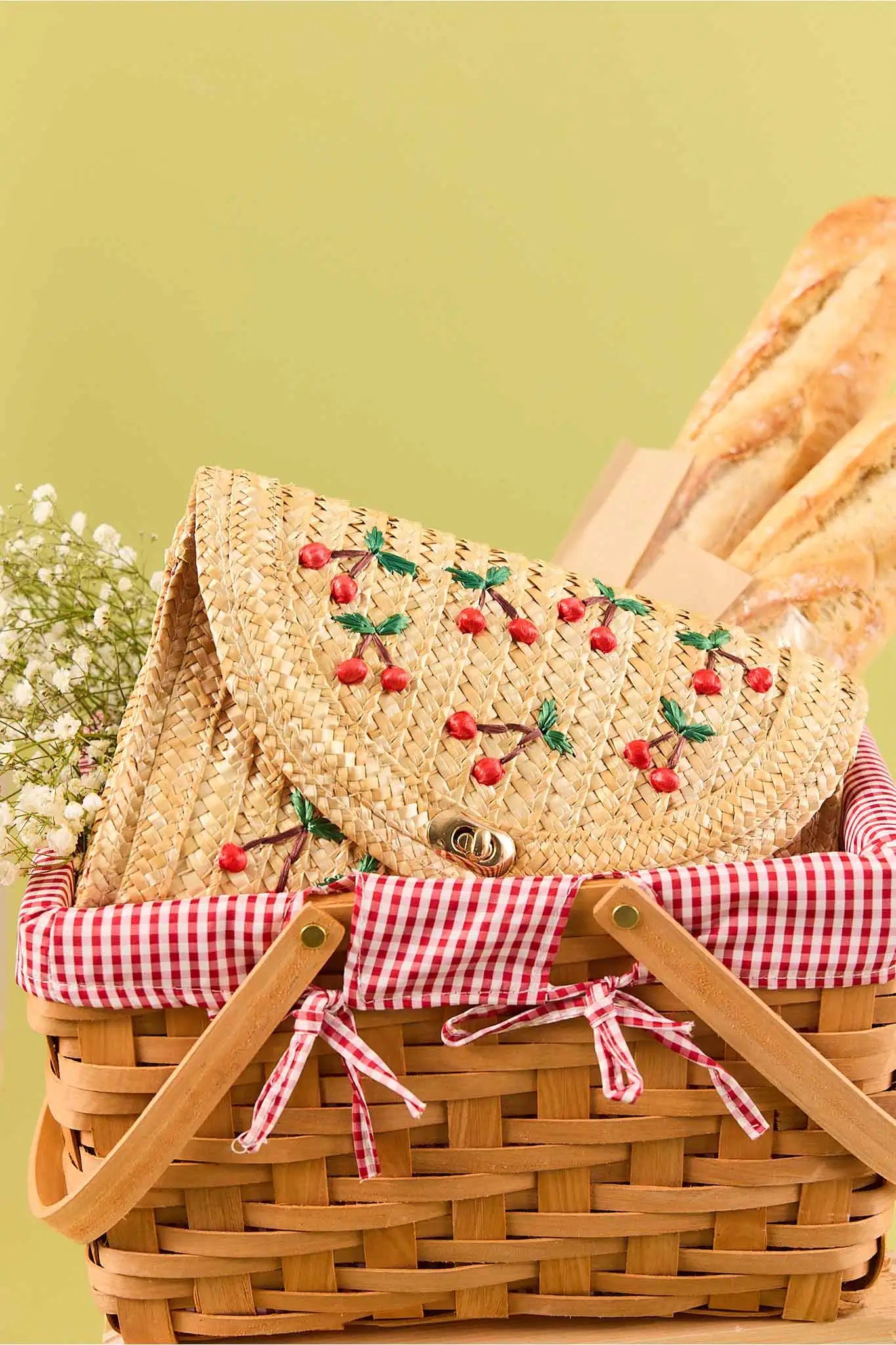 Wicker picnic basket with a straw lid featuring cherry design on a green background