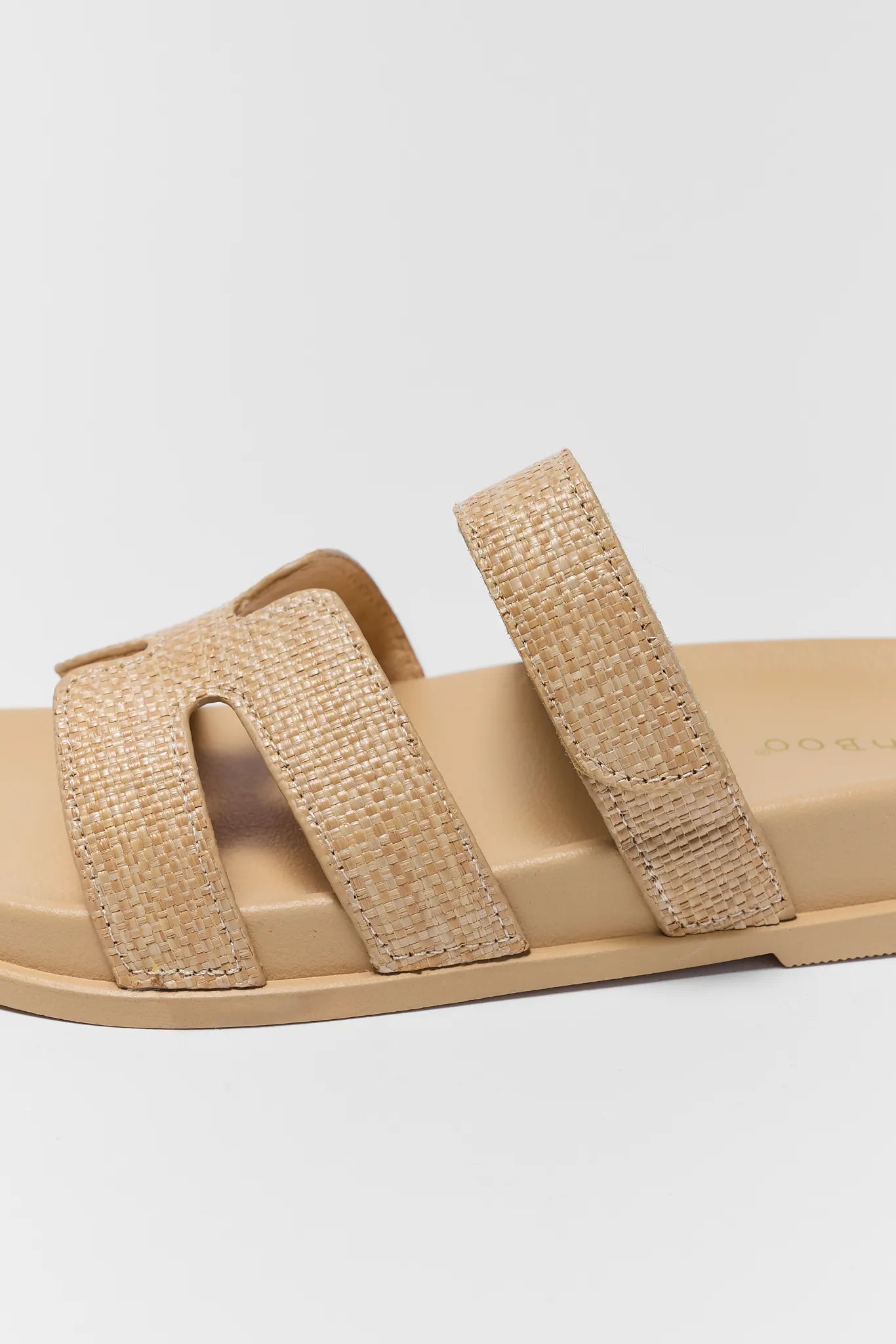 Beige sandal with woven straps on a light gray background