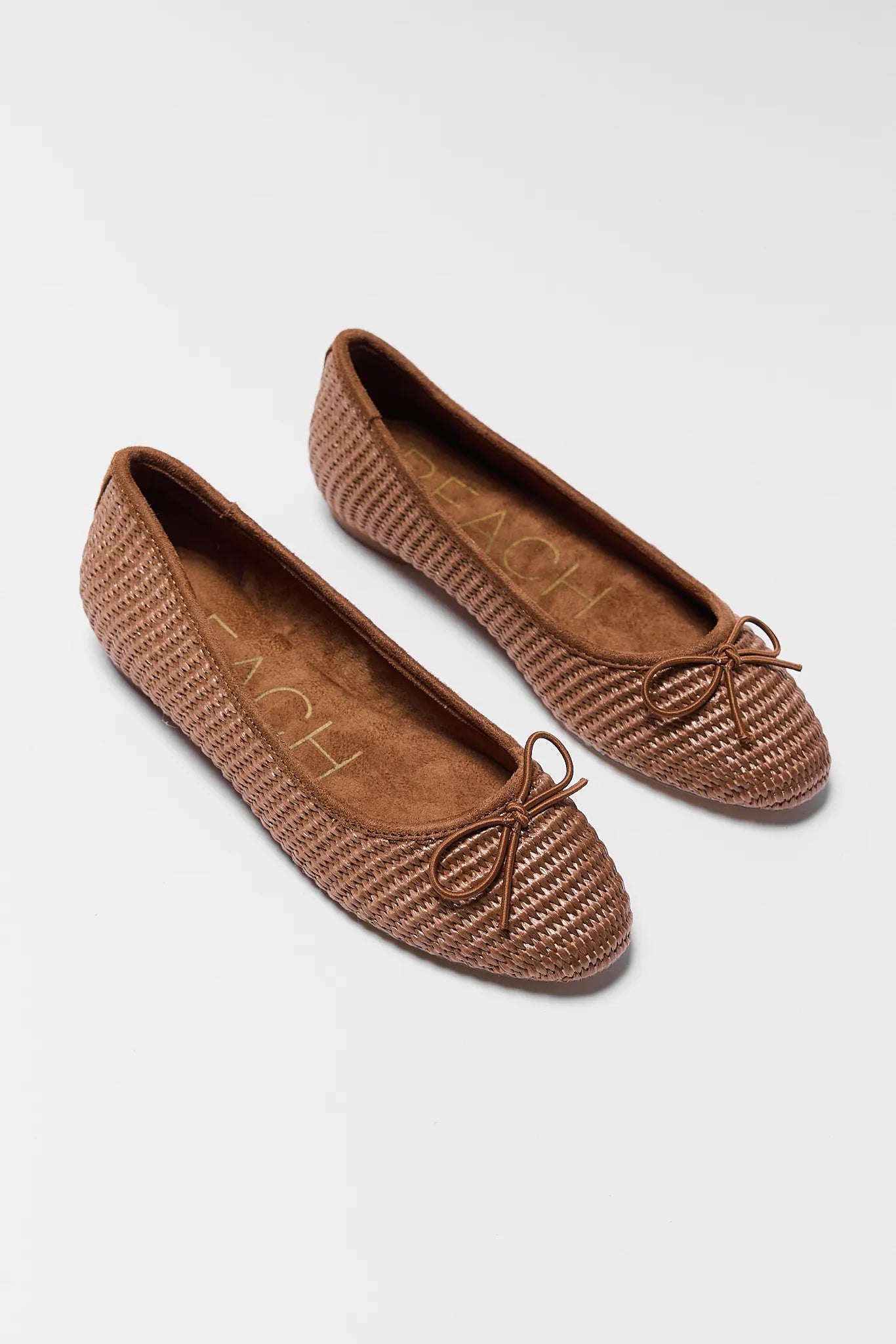 Pair of brown textured flats on a light gray background