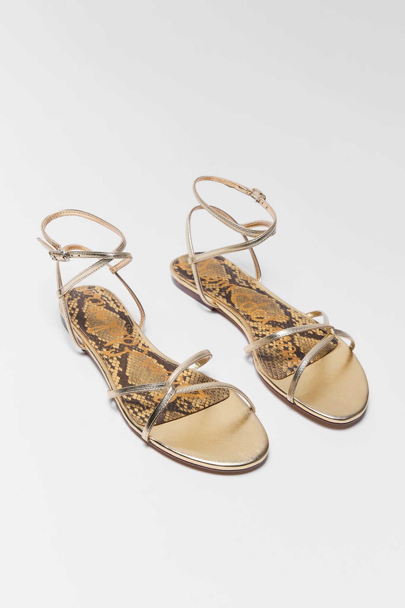 Gold snake print sandals on a white background