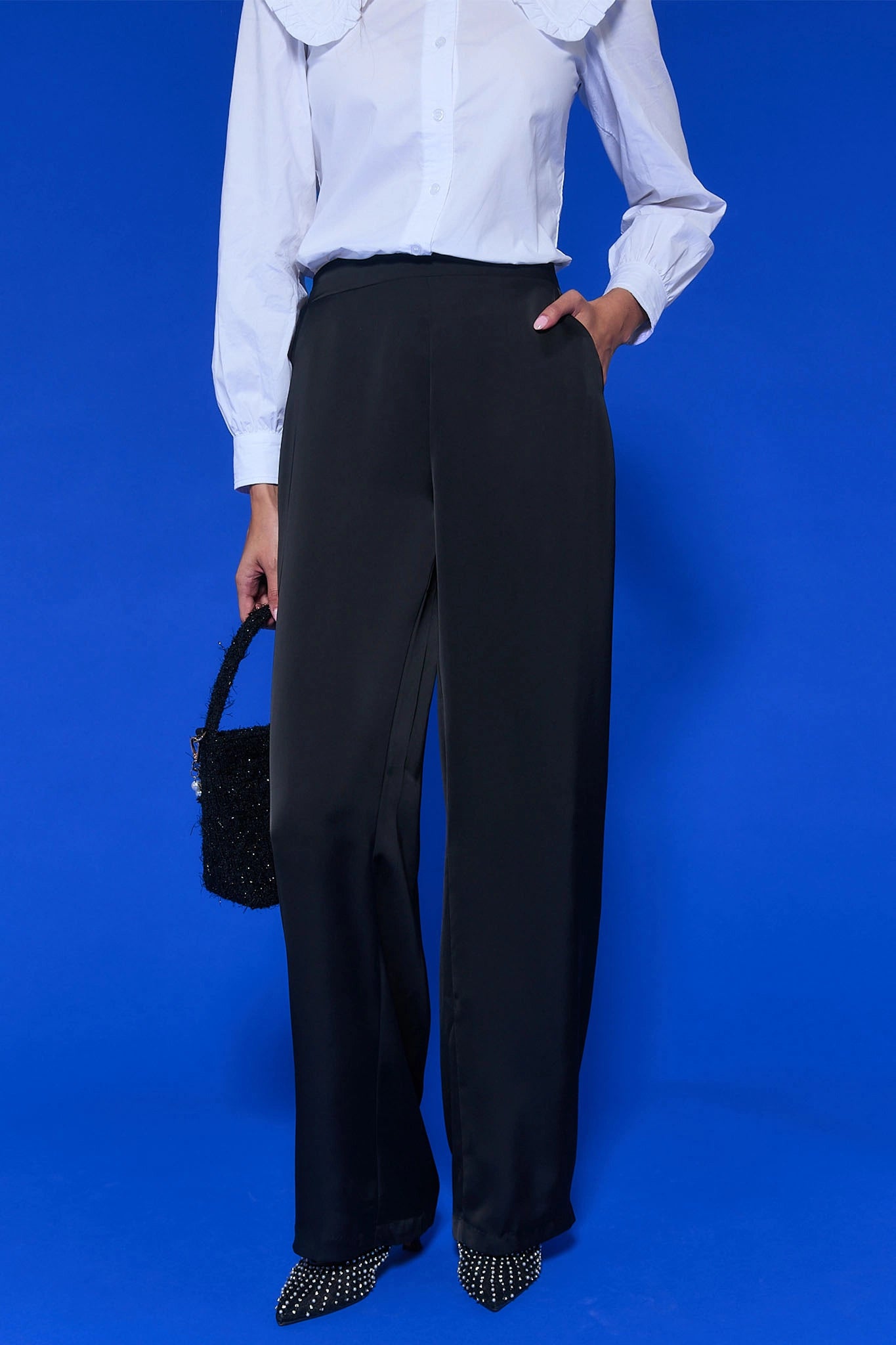 Person wearing a white shirt, Emerson Wide Leg Trousers, and black shoes against a blue background