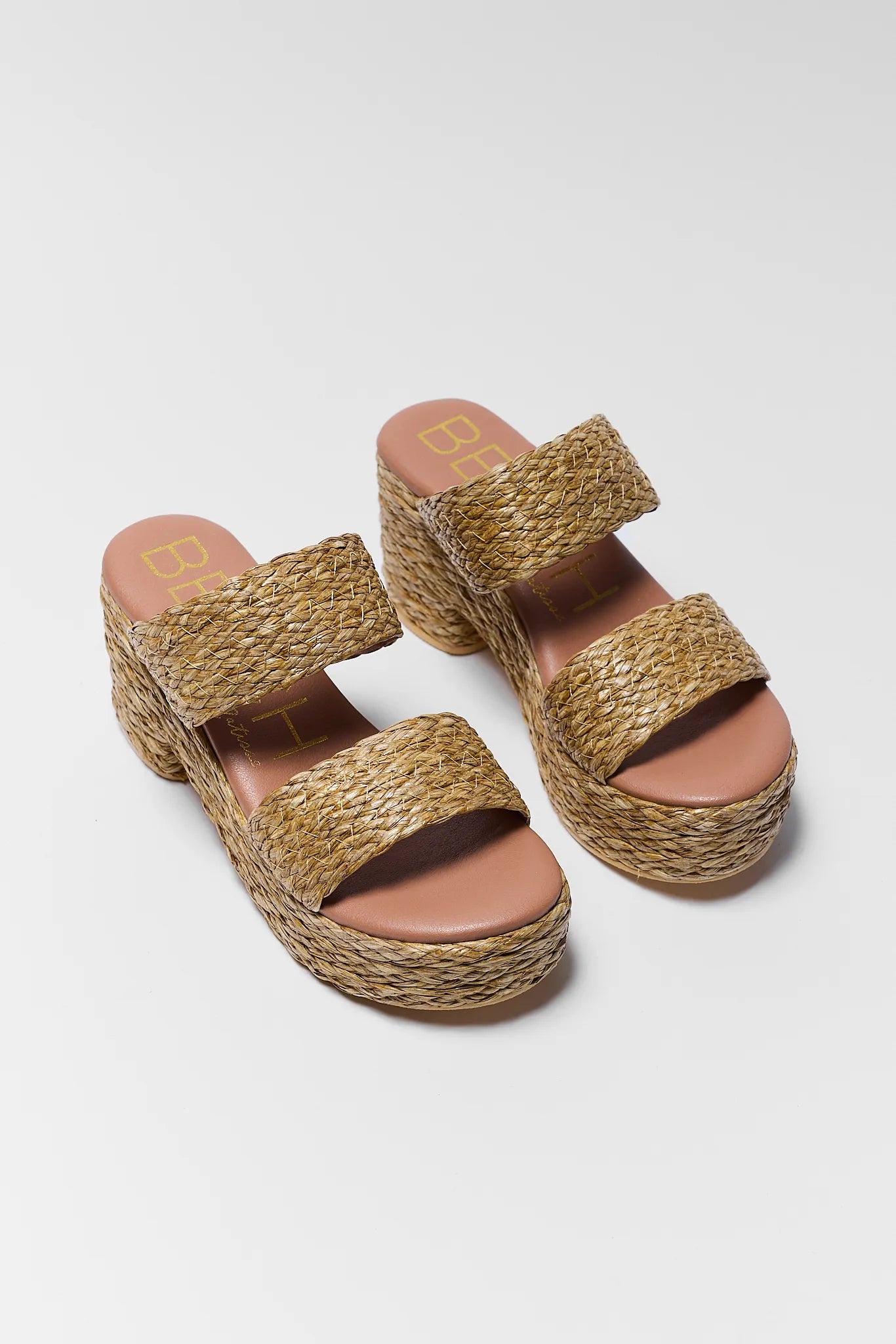 Pair of woven sandals with brown soles on a light gray background