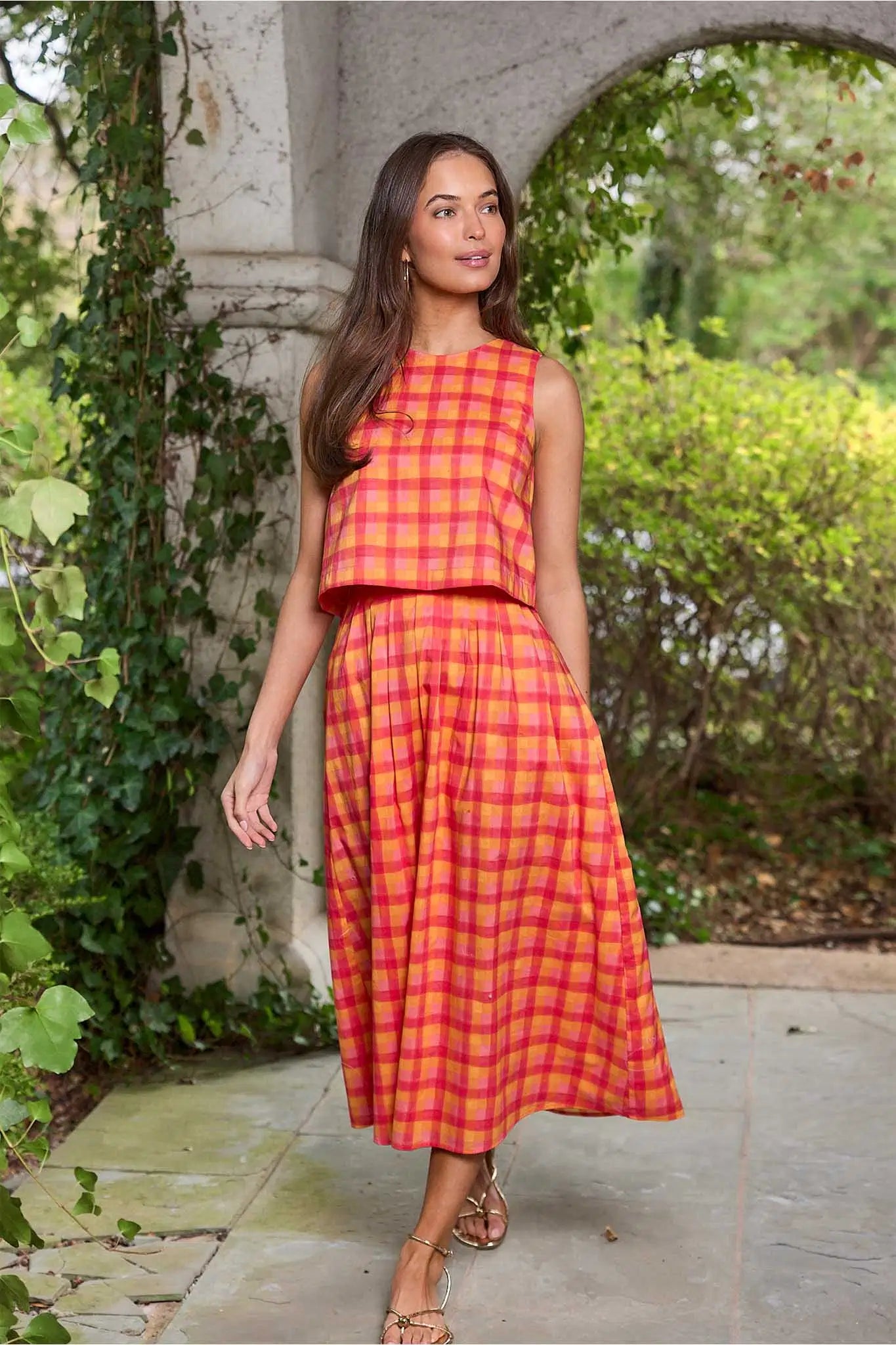 Woman wearing a red and yellow checkered dress standing outdoors.