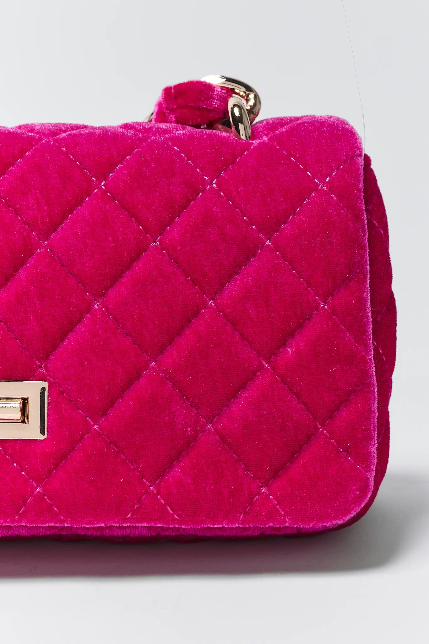 Quilted pink handbag with gold accents on a light gray background