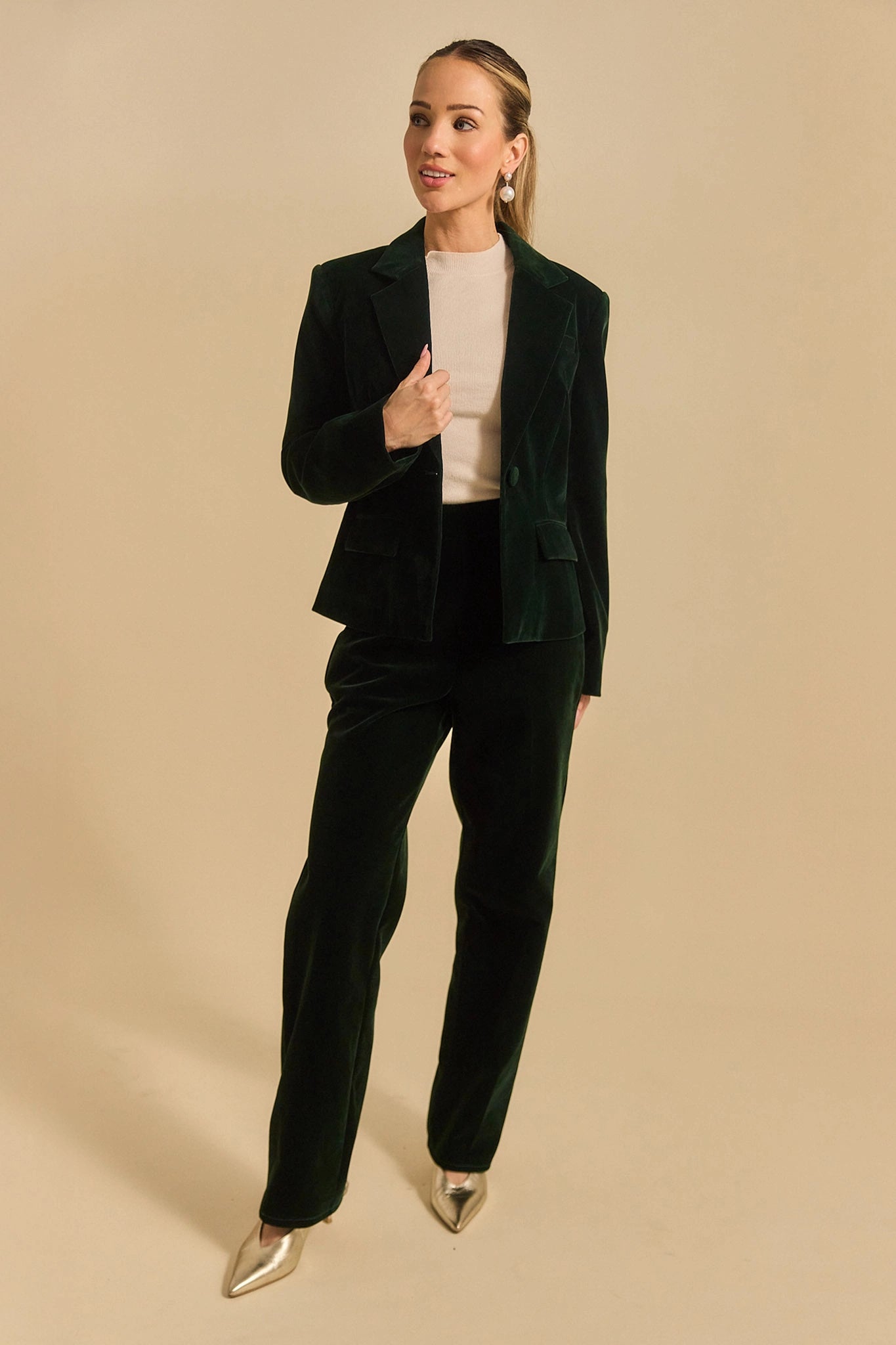 Woman wearing a green evie suit against a beige background