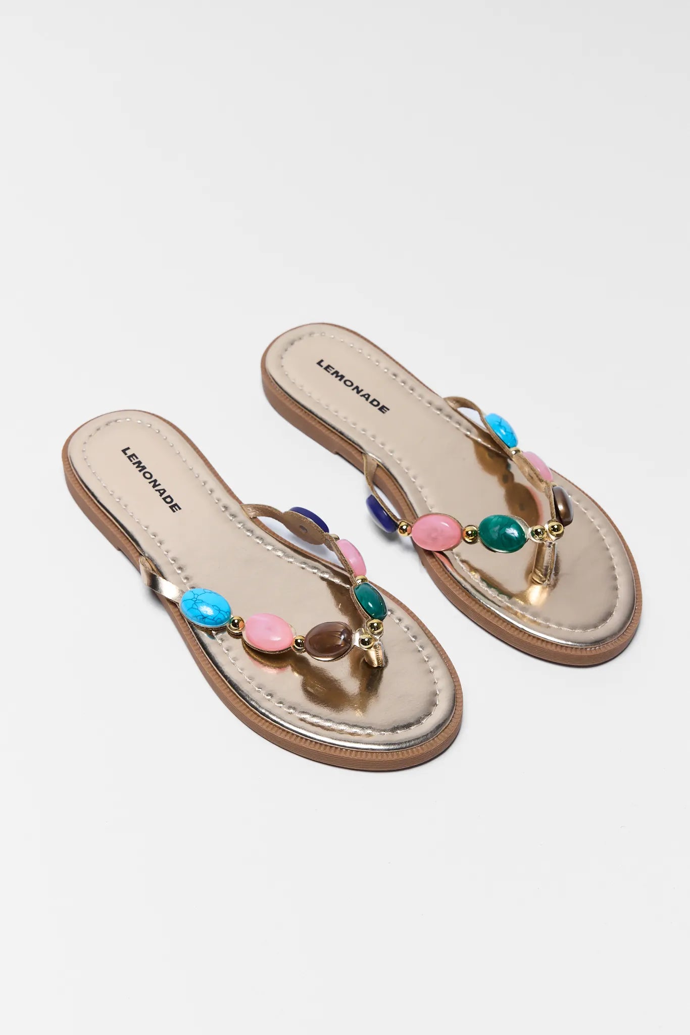 Pair of sandals with colorful beads on a light gray background