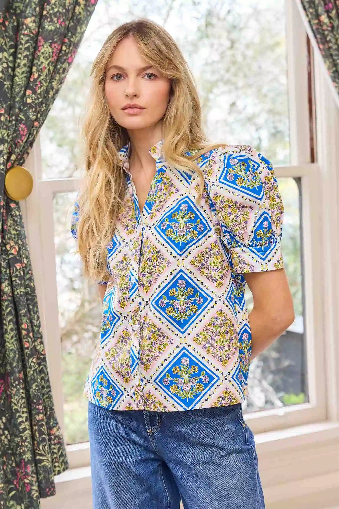 Woman wearing a patterned shirt with blue geometric design indoors.