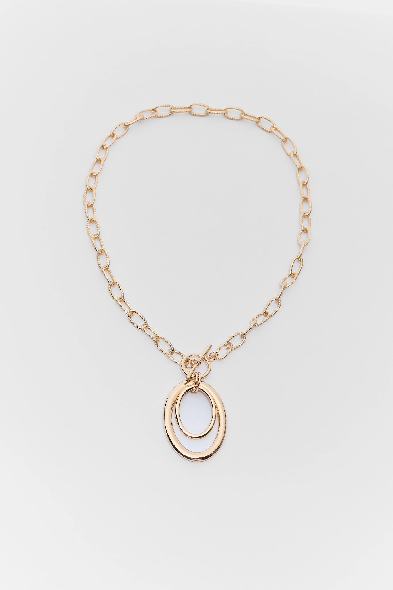 Gold chain necklace with a pendant on a light gray background