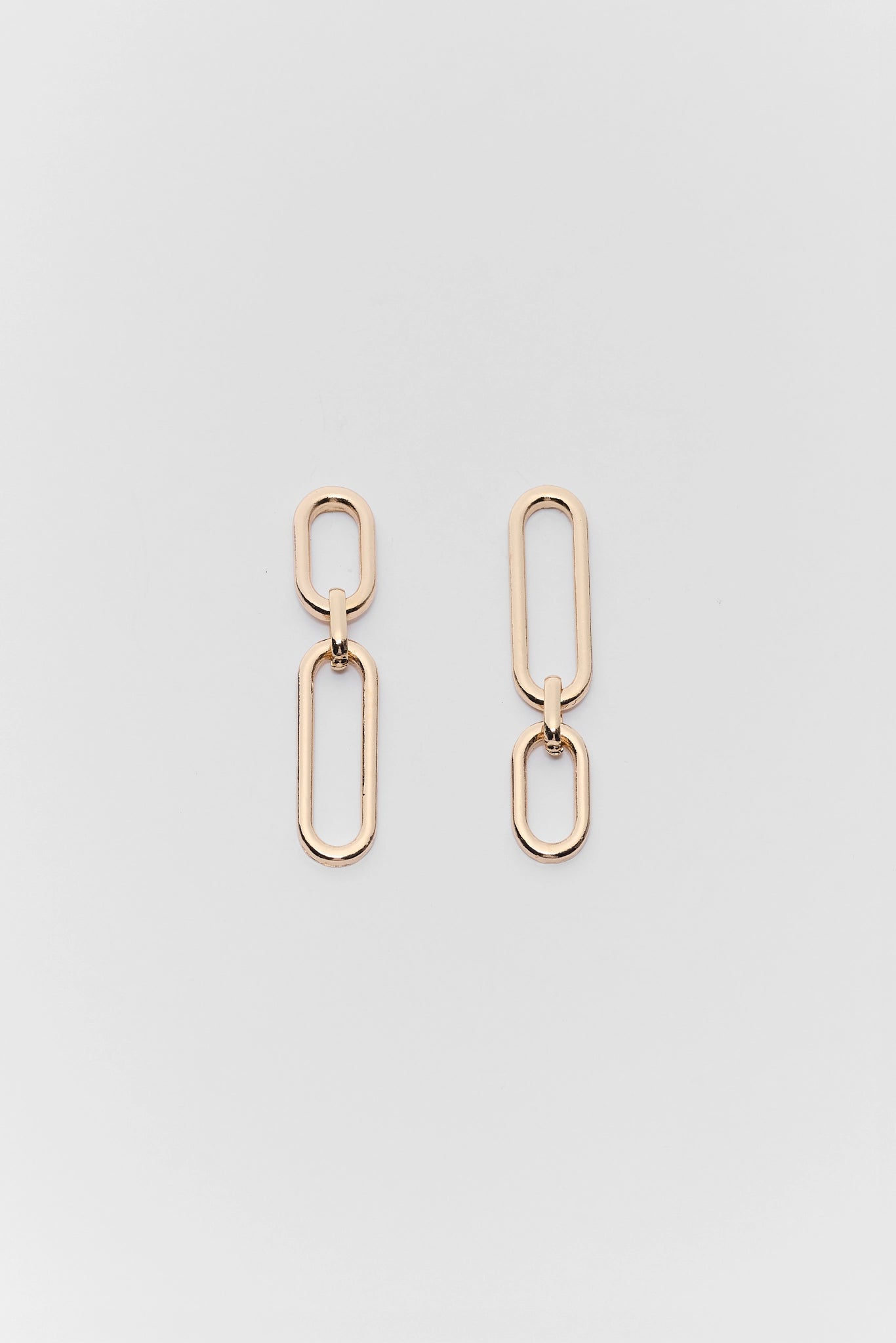Gold chain link earrings on a light gray background