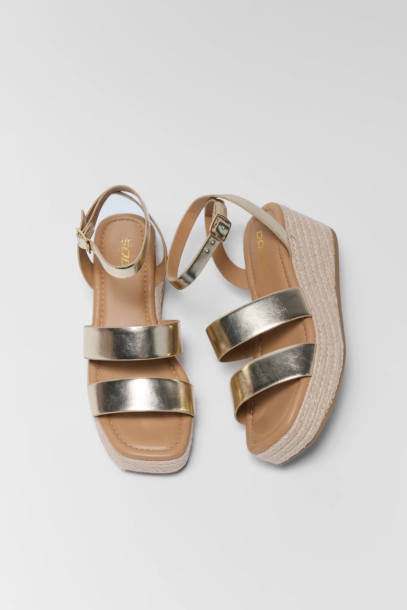 Pair of sandals with metallic straps on a light gray background