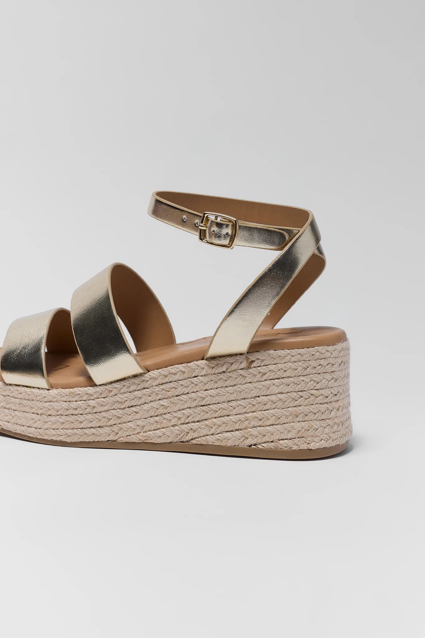 close up Gold platform sandal with espadrille sole on a light gray background